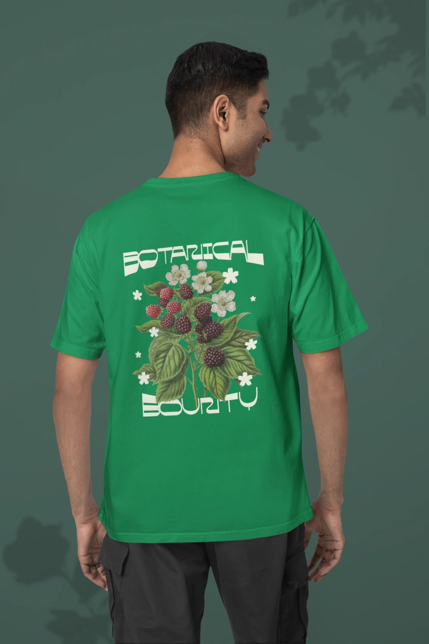 Back view of a male model model wearing a forest green with a design featuring berry bushes overflowing with fruit, symbolizing the abundance and beauty of nature.