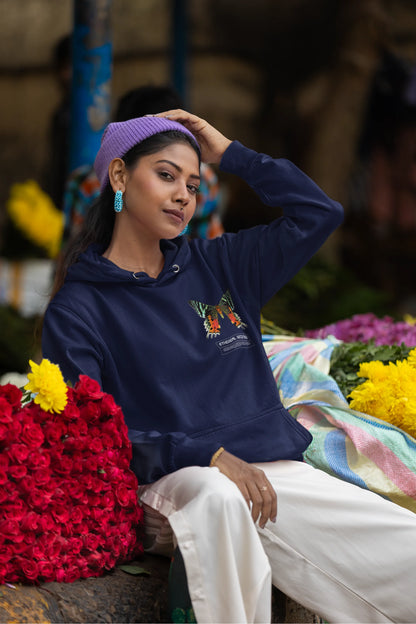 Fourth front view of a female model wearing a navy blue hoodie with a glowing butterfly design, symbolizing the ethereal beauty of nature.