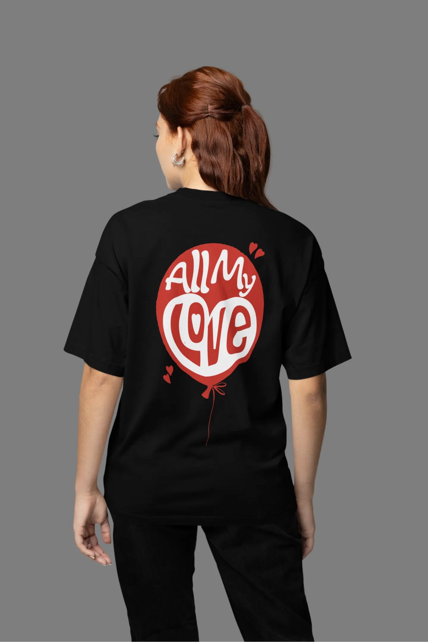 Back view of a female model wearing a black oversized t-shirt with a heart design and the text "All My Love".