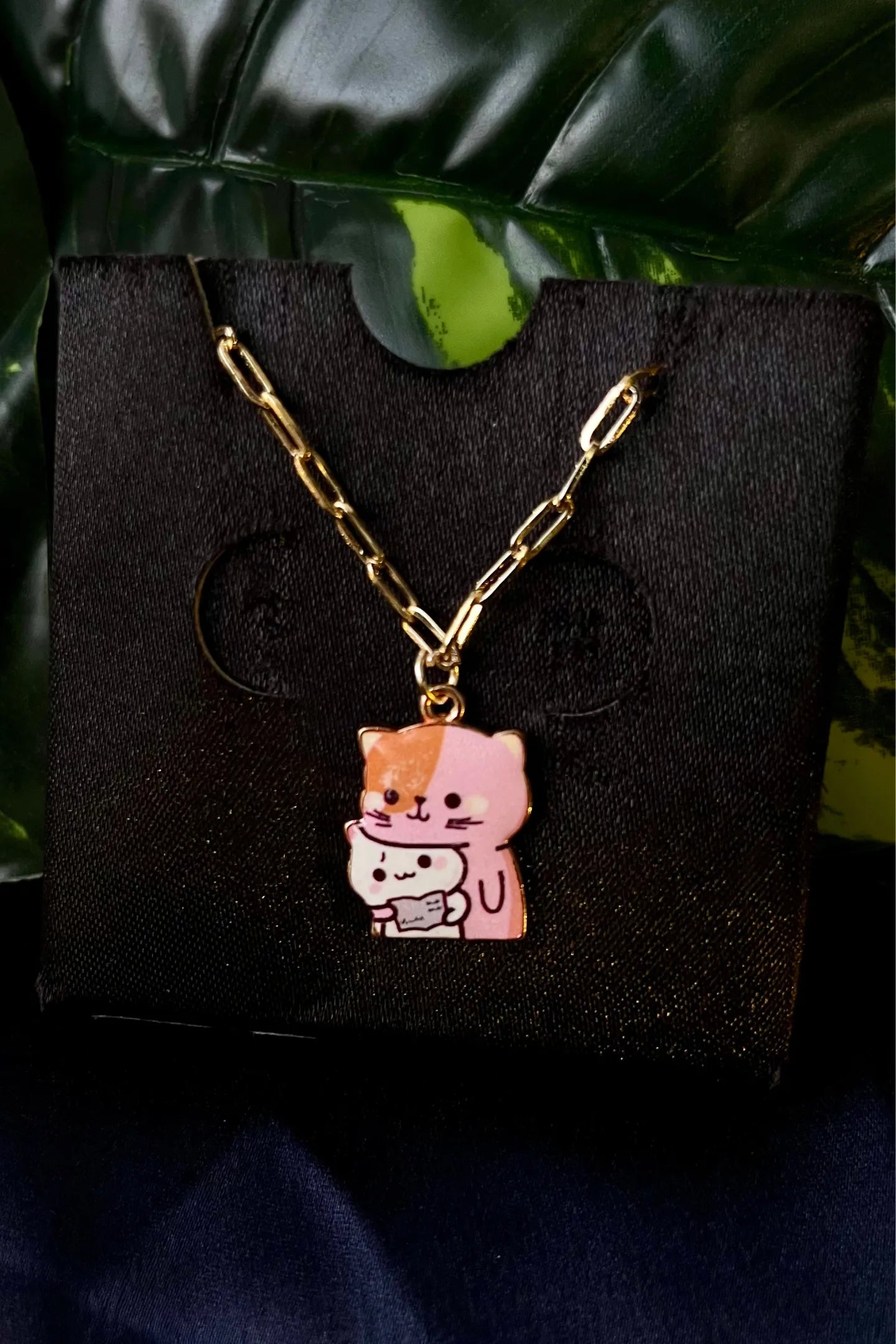 Third view of an anti tarnish gold chain necklace featuring a design of a mother cat and her kitten.