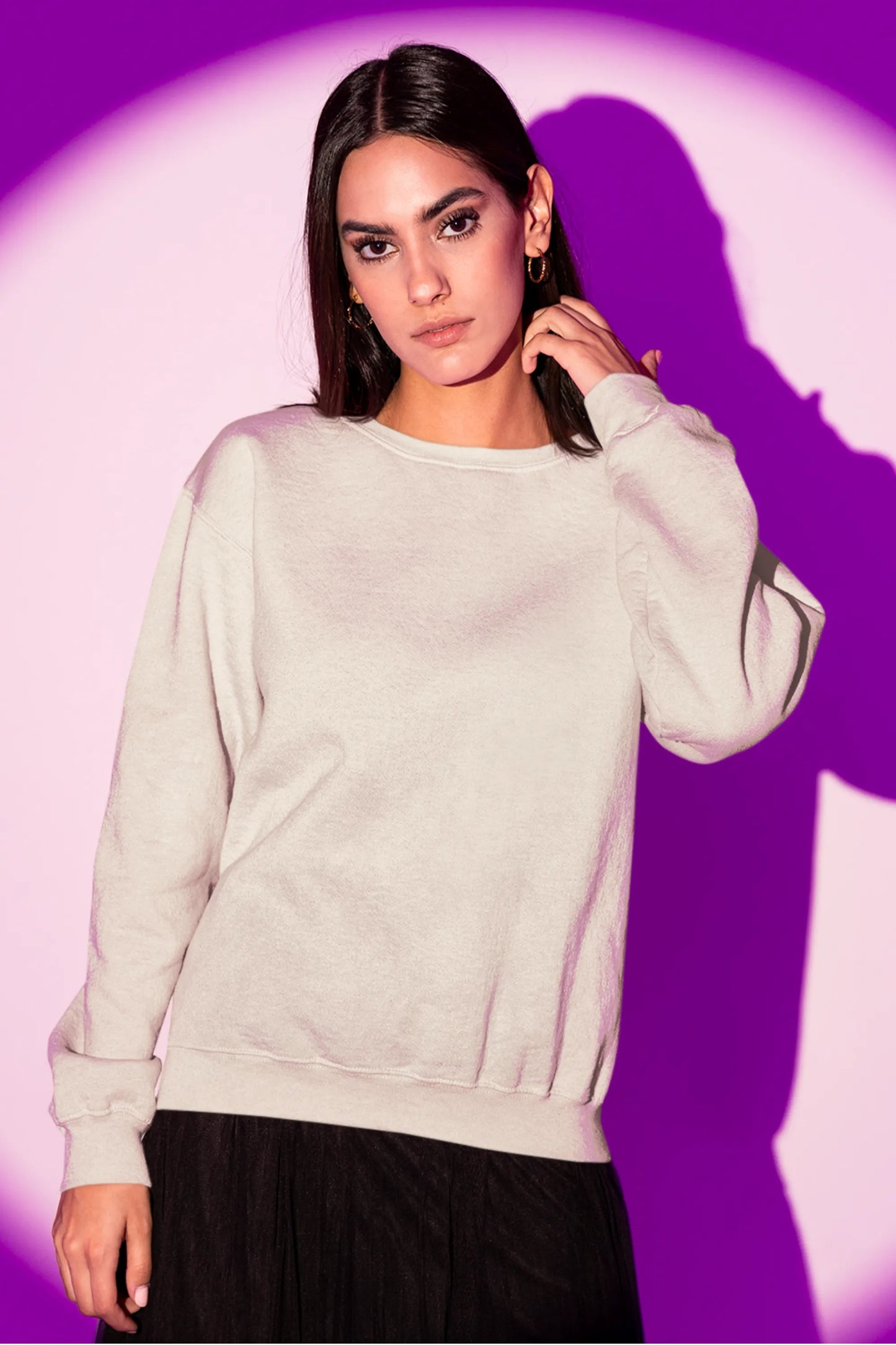 Front view of a female model wearing an cream sweatshirt featuring a detailed illustration of a gray wolf howling at a full moon in a nighttime setting.