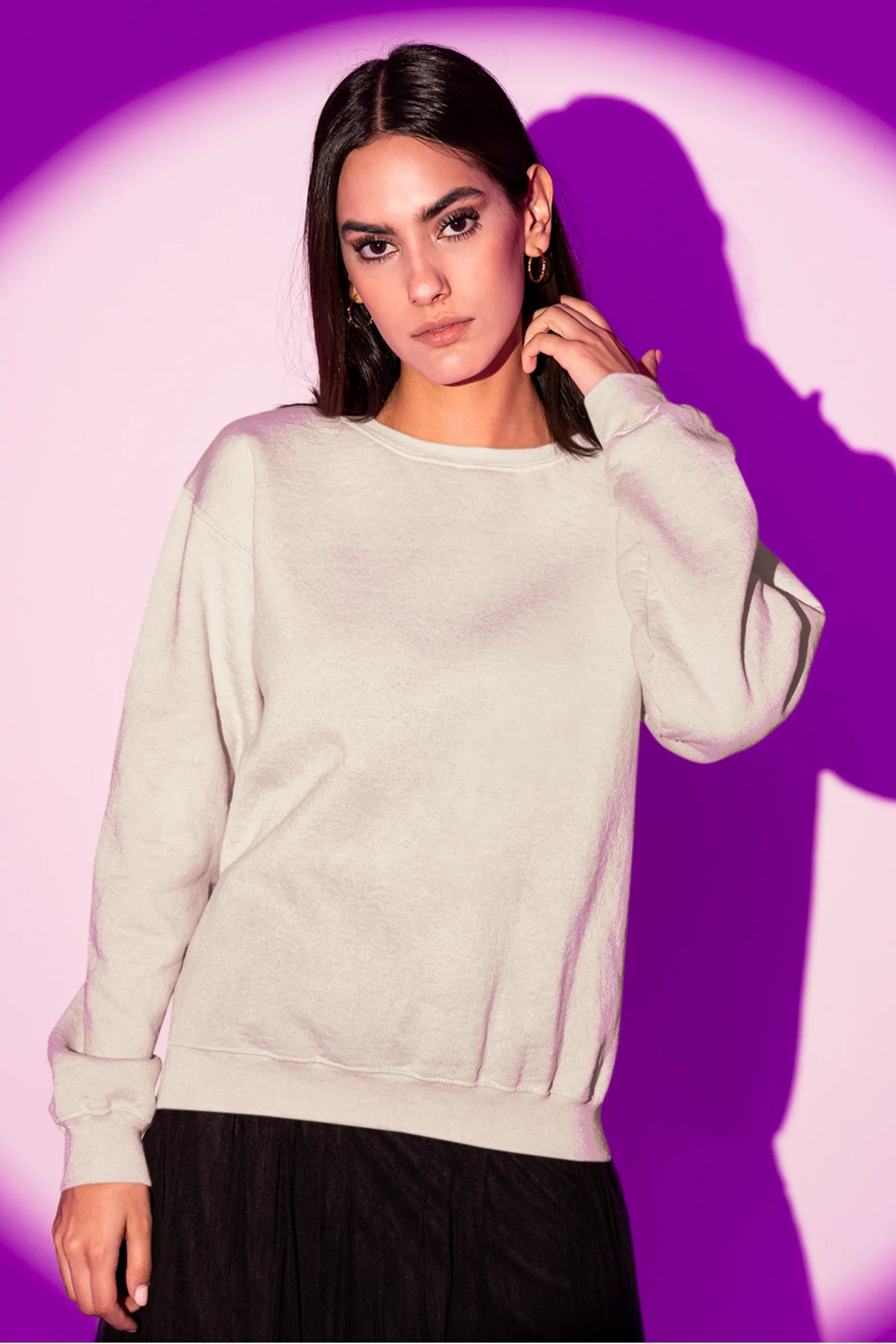 Front view of a female model wearing an cream sweatshirt featuring a detailed illustration of a gray wolf howling at a full moon in a nighttime setting.