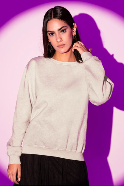 Front view of a female model wearing an cream sweatshirt featuring a detailed illustration of a gray wolf howling at a full moon in a nighttime setting.