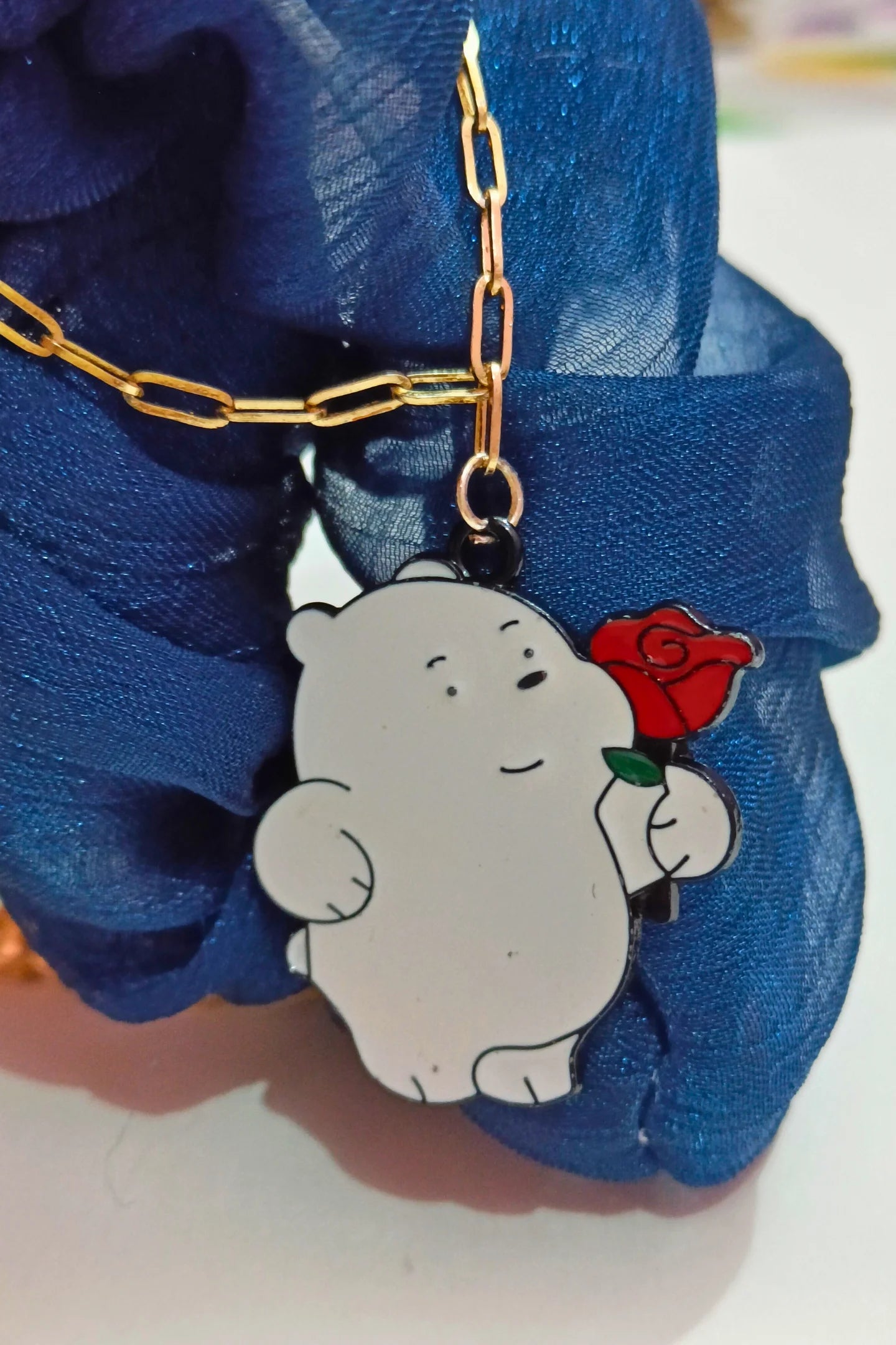 First view of a gold chain necklace with a small pendant of Ice Bear from a cartoon, holding a rose.