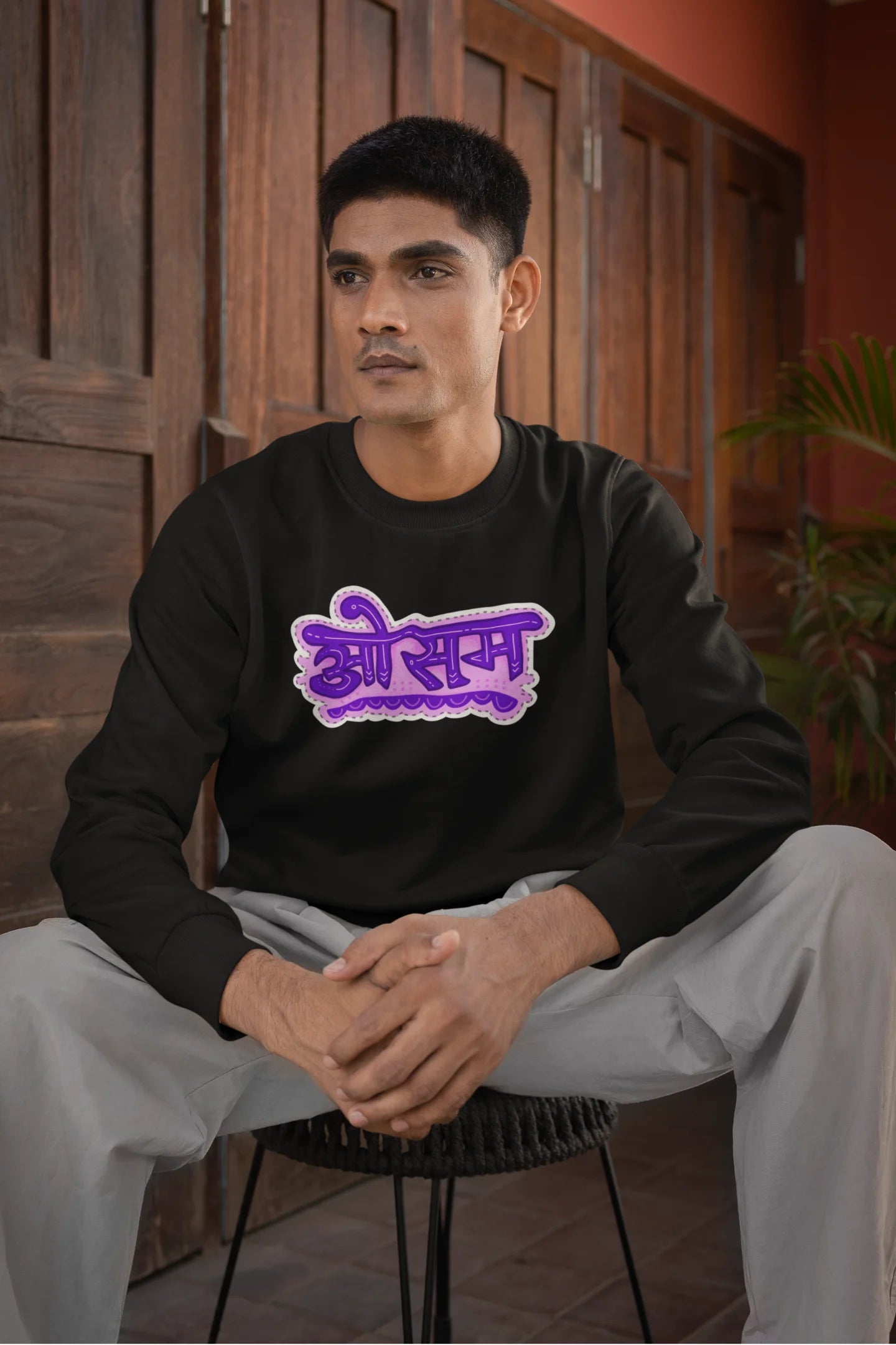 4th front view of a male model wearing a black colored oversized graphic t-shirt featuring the word "awesome" in a Hindi script.