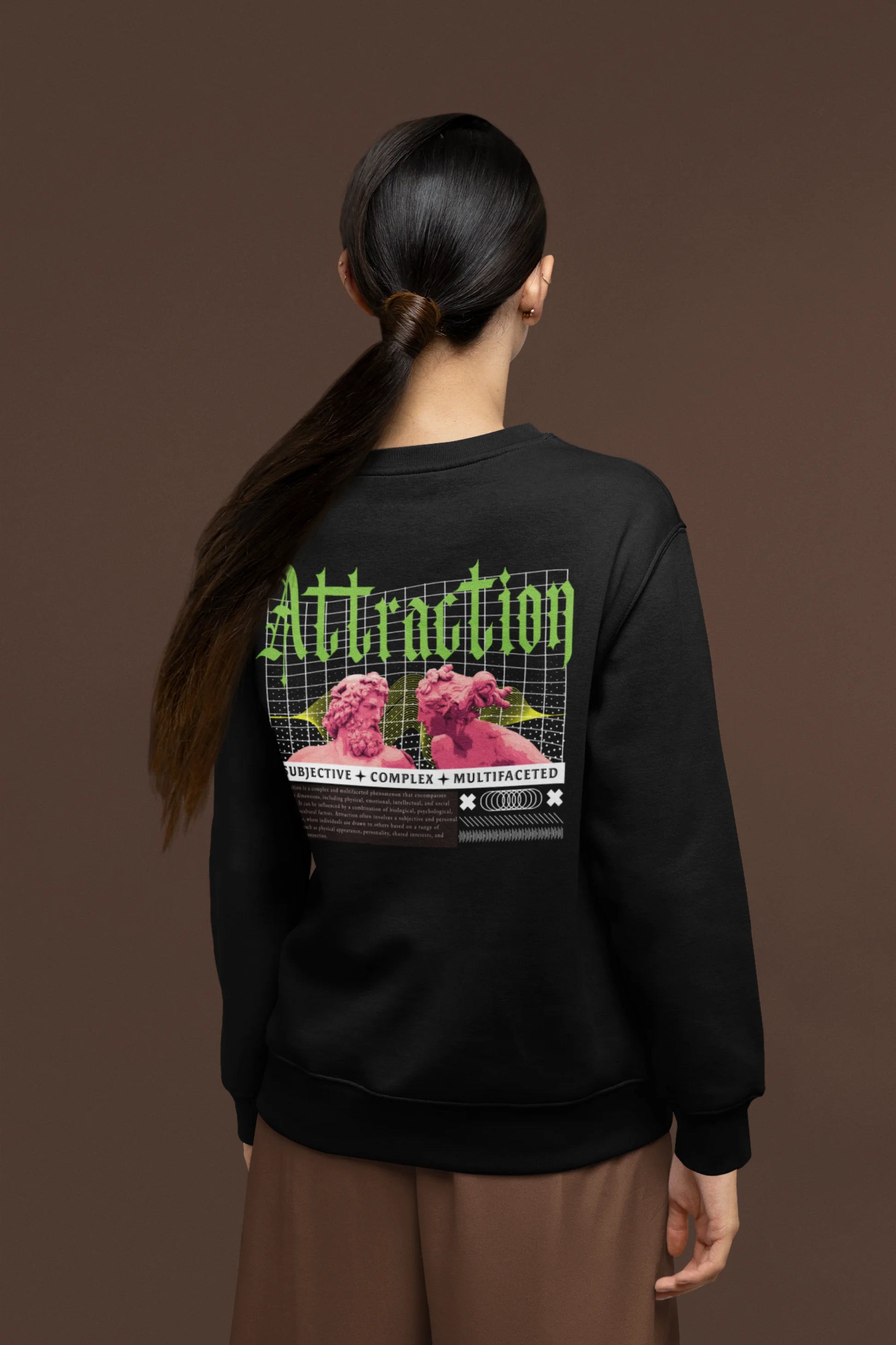 Back view of a female model wearing a black sweatshirt with a brutalist design featuring two statues kissing and the word "Attraction".