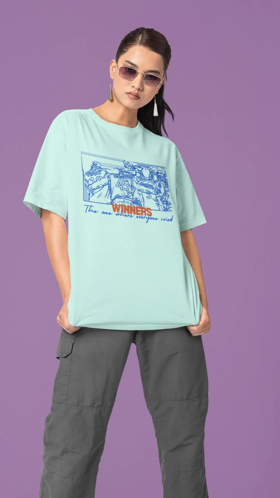 Right side view of a female model wearing an mint-green oversized t-shirt featuring a design of the Indian cricket team in a celebratory huddle with the text "Winners" above them. Ideal for Indian cricket fans commemorating their team's World Cup victory.