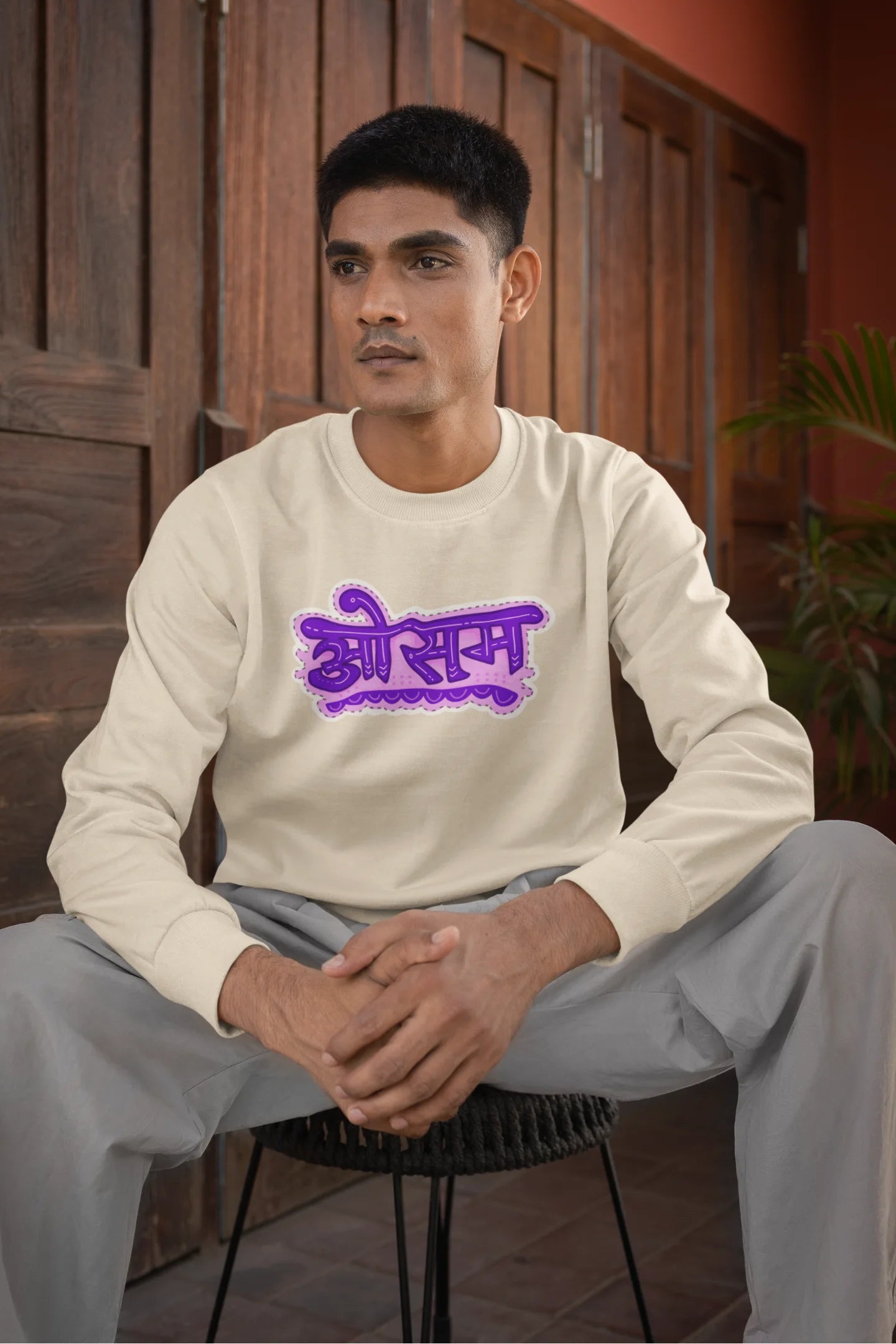 5th front view of a male model wearing a cream colored oversized graphic t-shirt featuring the word "awesome" in a Hindi script.