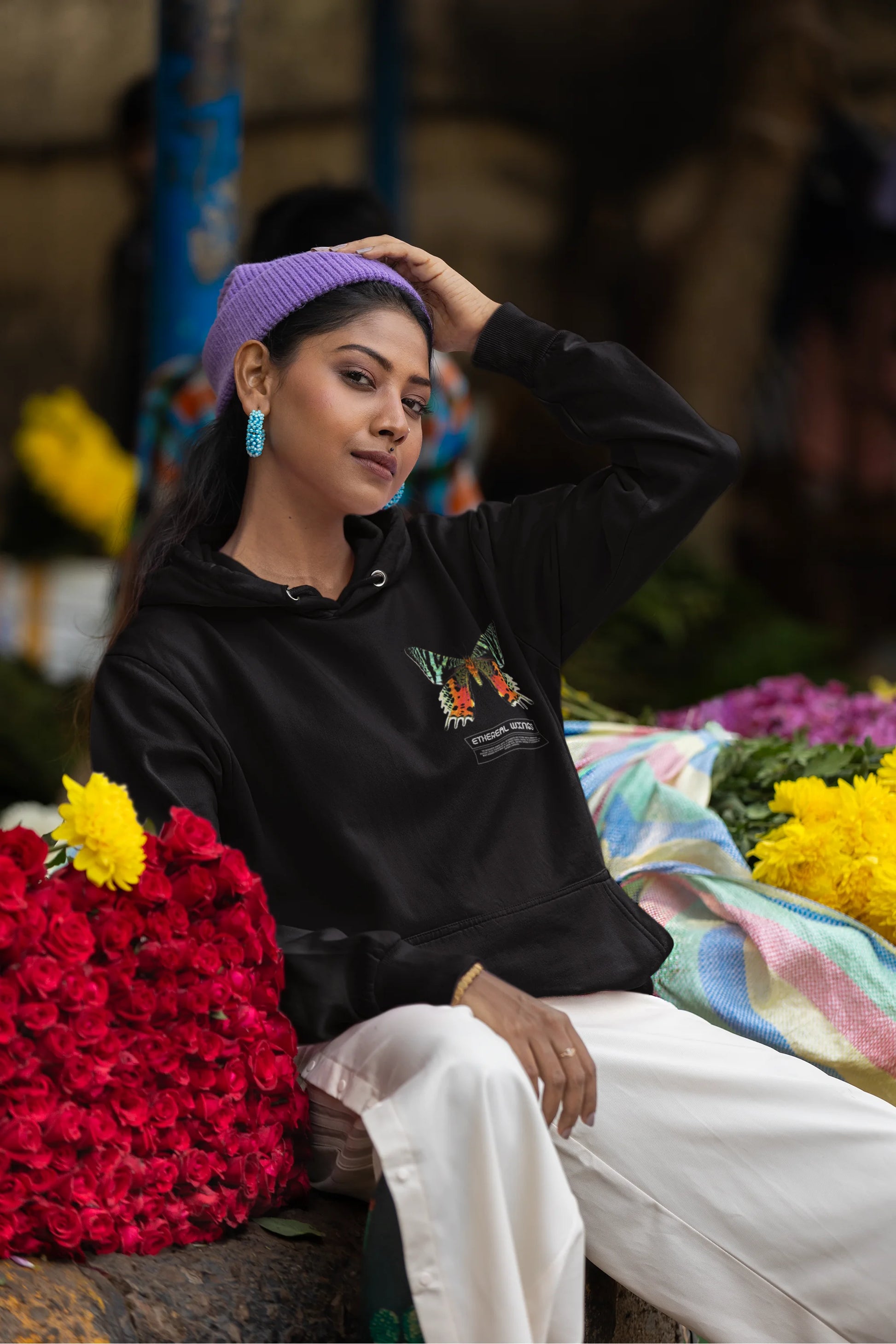 Fifth front view of a female model wearing a black hoodie with a glowing butterfly design, symbolizing the ethereal beauty of nature.