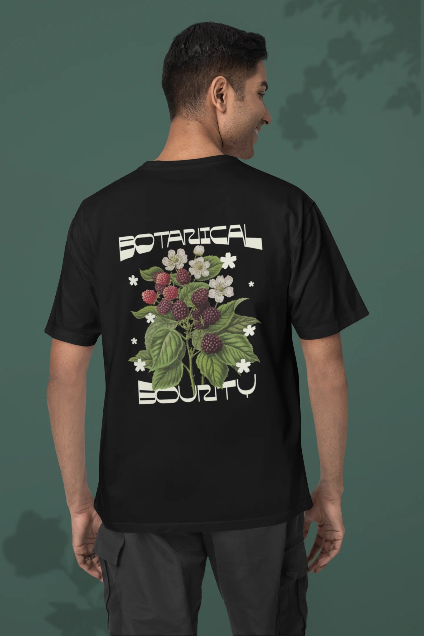 Back of a male model model wearing a black with a design featuring berry bushes overflowing with fruit, symbolizing the abundance and beauty of nature.