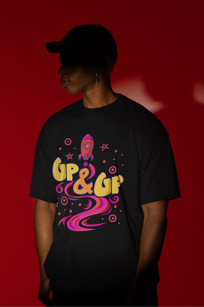 First front view of a male model wearing an black oversized t-shirt with a rocket ship design and the text "Up & Up".