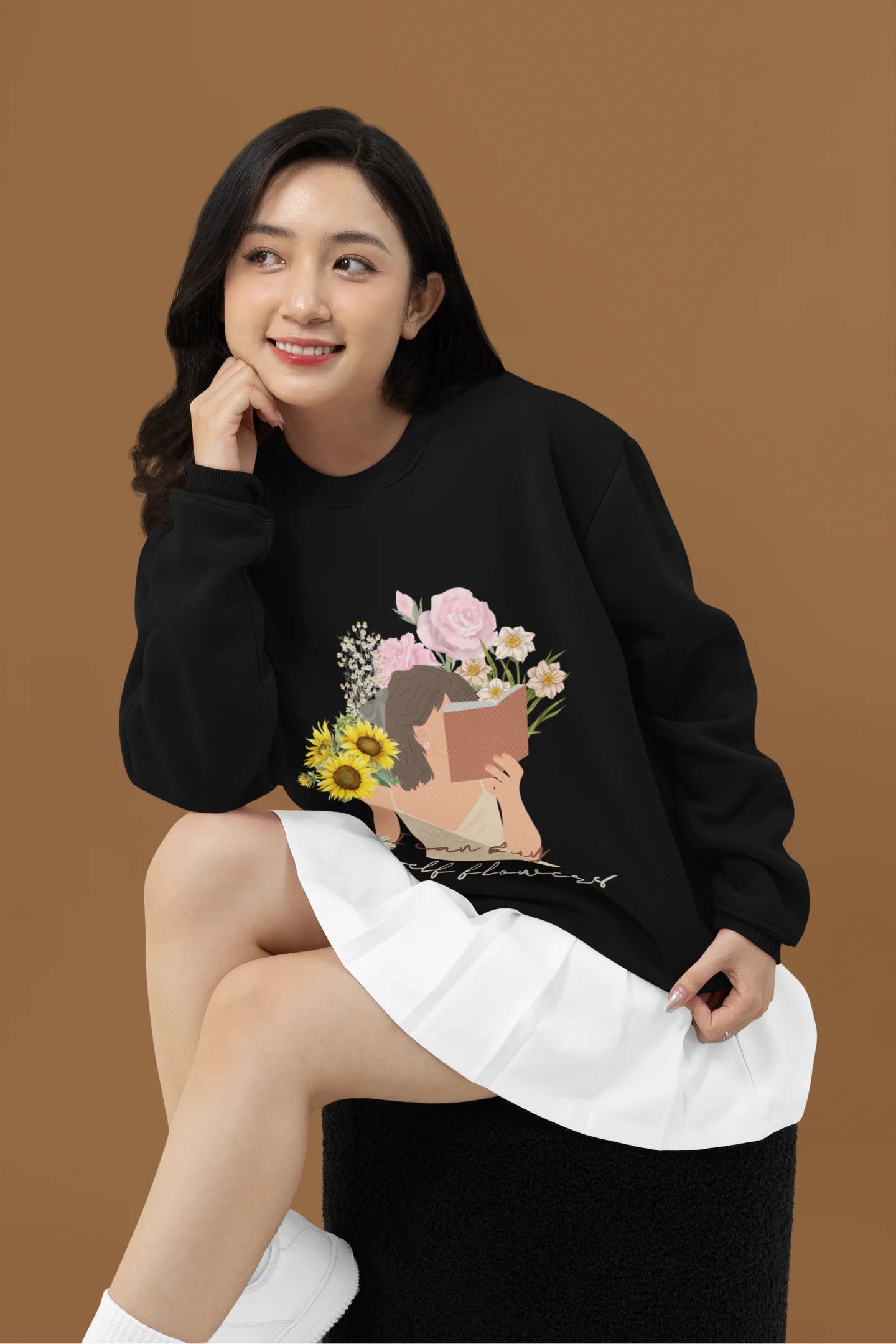 3rd front view of female model wearing a black sweatshirt with a positive message "Buy Myself Flowers" and a graphic of a smiling woman surrounded by tulips and sunflowers. Ideal for those who love inspirational clothing and floral designs.