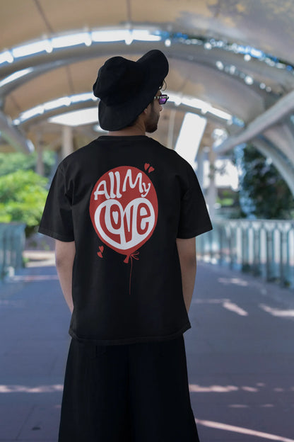 Back view of a male model wearing a black oversized t-shirt with a heart design and the text "All My Love".