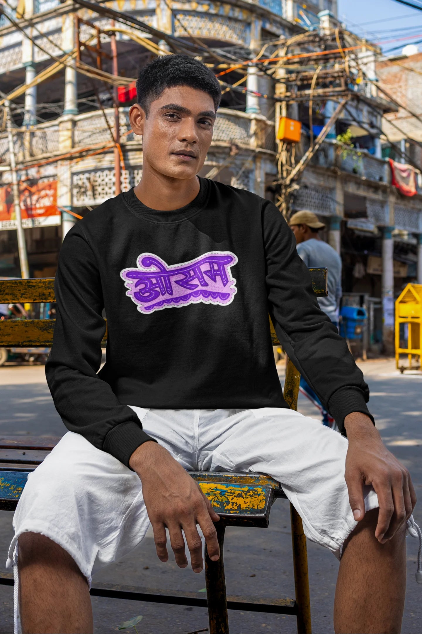 5th front view of a male model wearing a black colored oversized graphic t-shirt featuring the word "awesome" in a Hindi script.