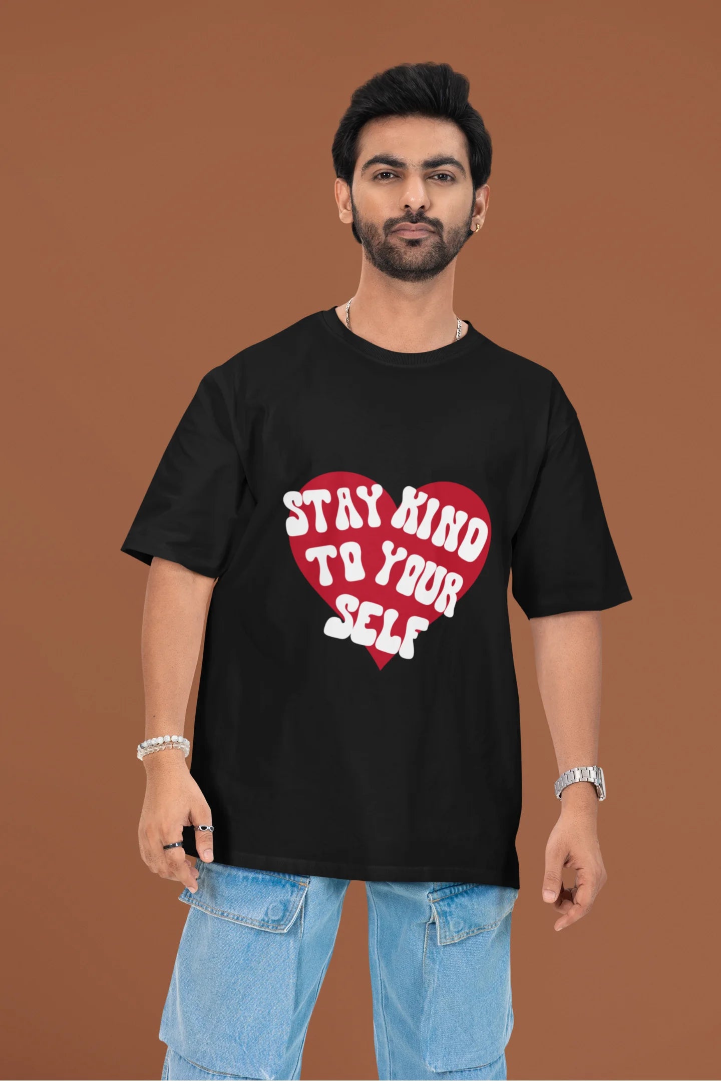 3rd front view of a male model wearing a black oversized t-shirt with the text "Stay Kind" printed on it.