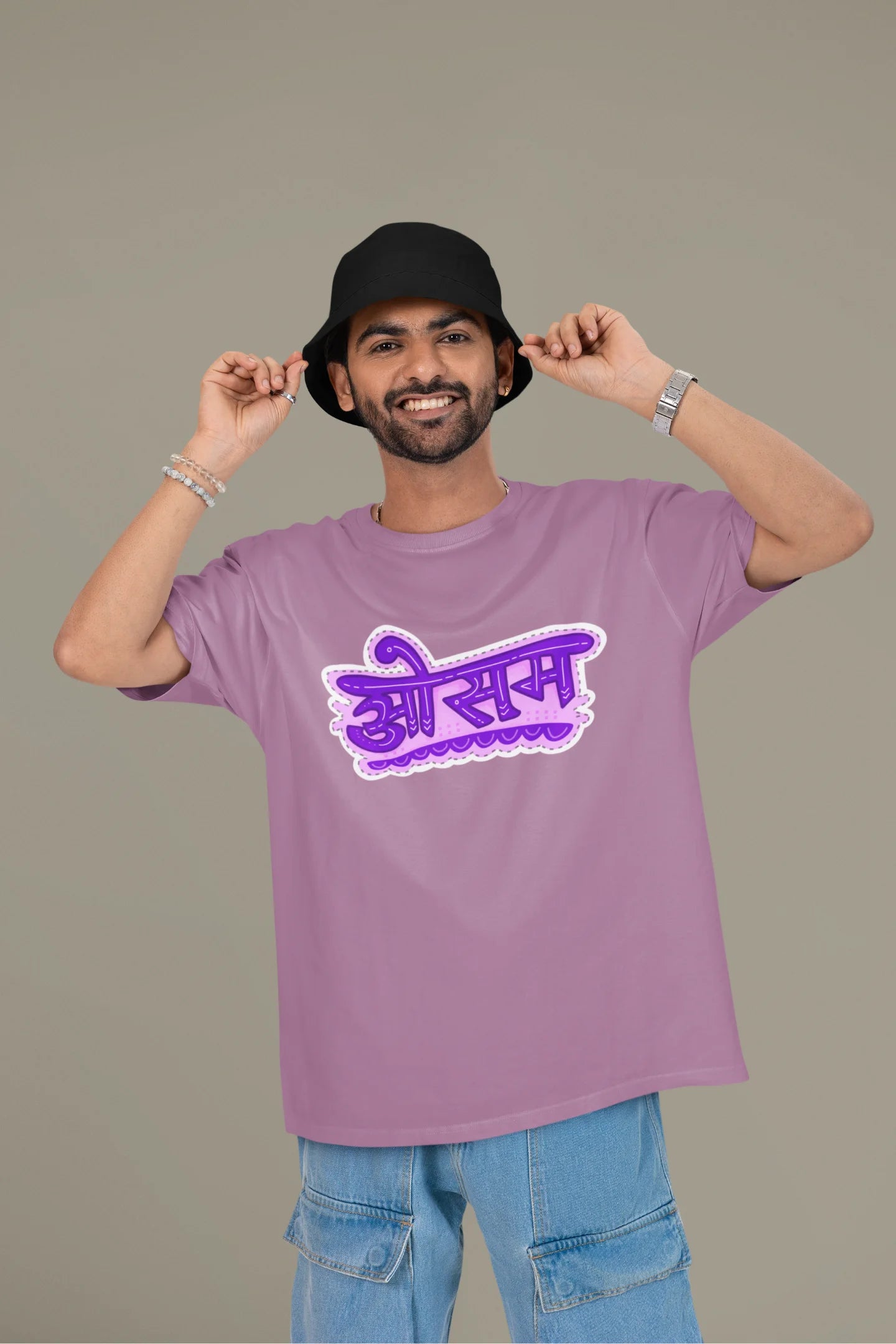 First front view of a male model wearing a dirty purple colored oversized graphic t-shirt featuring the word "awesome" in a Hindi script.