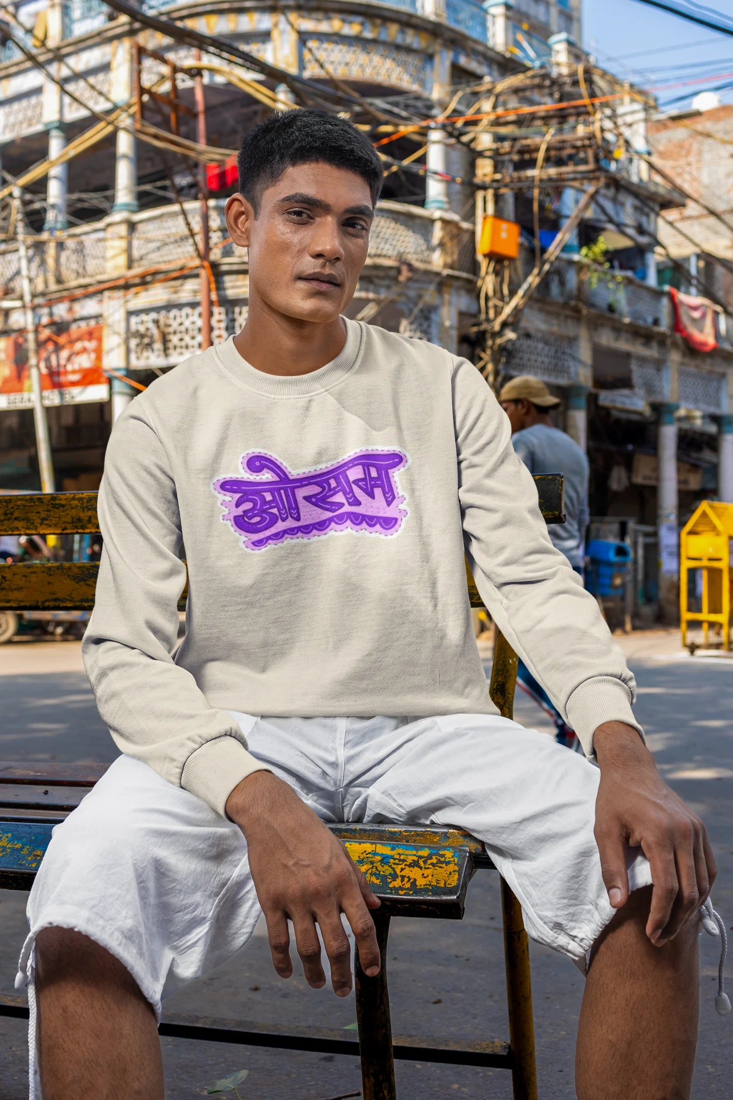 4th front view of a male model wearing a cream colored oversized graphic t-shirt featuring the word "awesome" in a Hindi script.