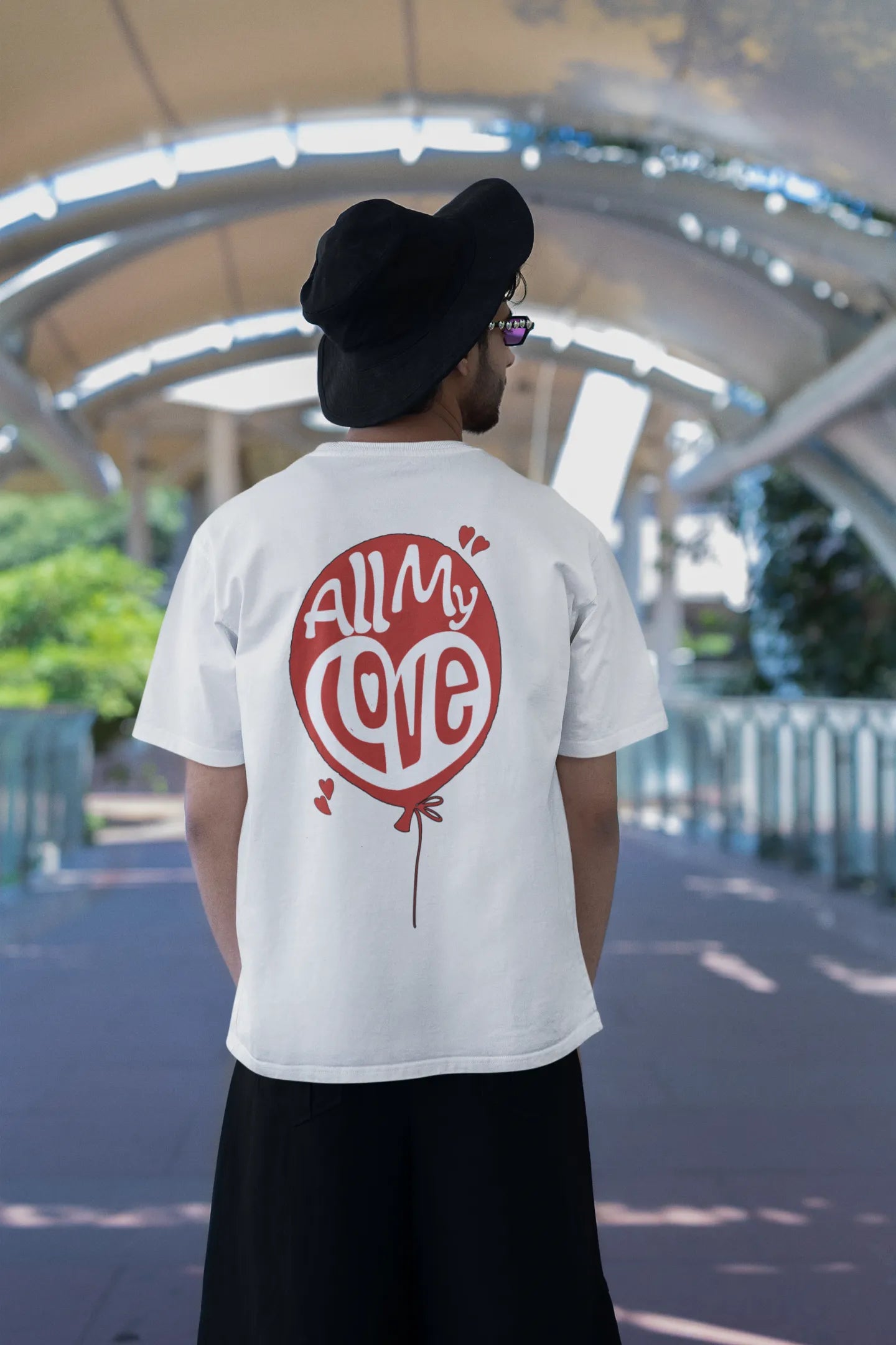 Back view of a male model wearing a off-white oversized t-shirt with a heart design and the text "All My Love".