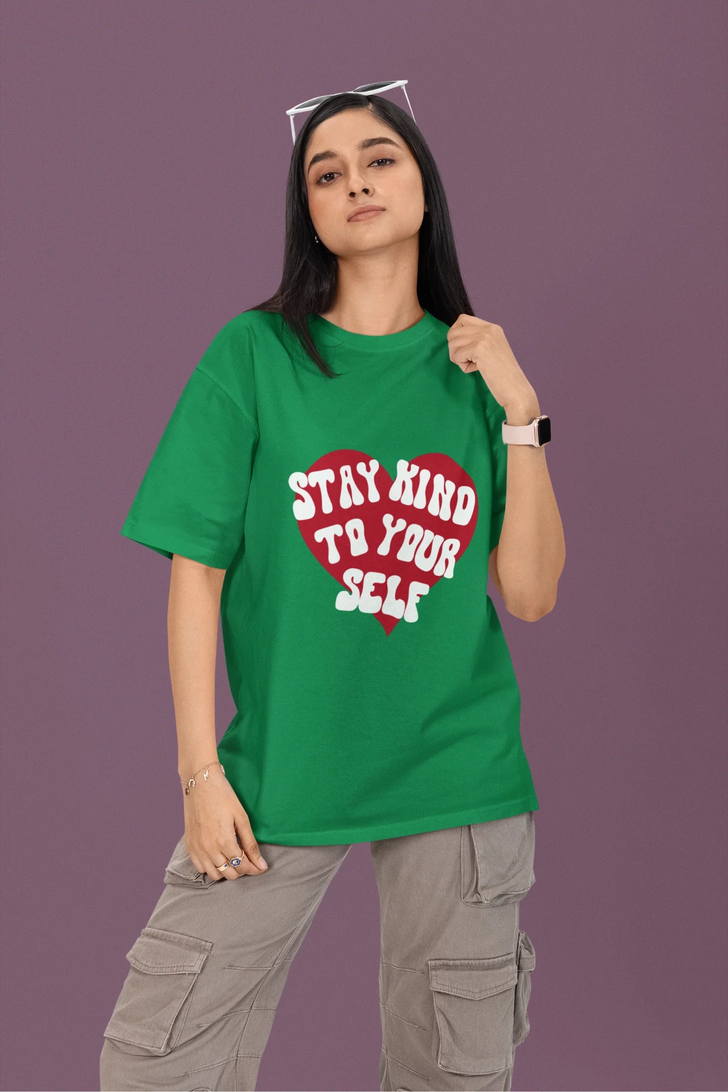 First front view of a female model wearing a forest green oversized t-shirt with the text "Stay Kind" printed on it.