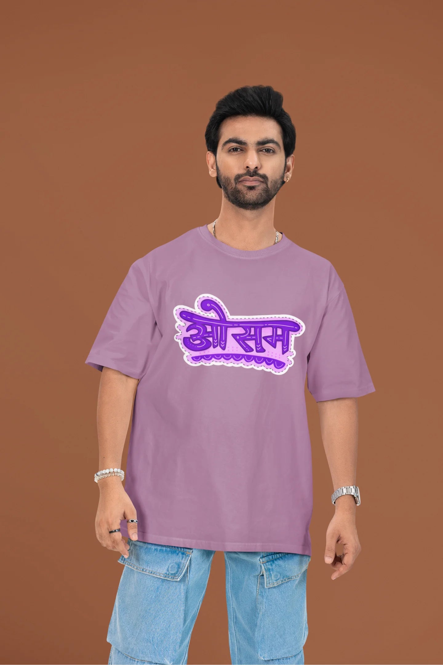 2nd front view of a male model wearing a dirty purple colored oversized graphic t-shirt featuring the word "awesome" in a Hindi script.