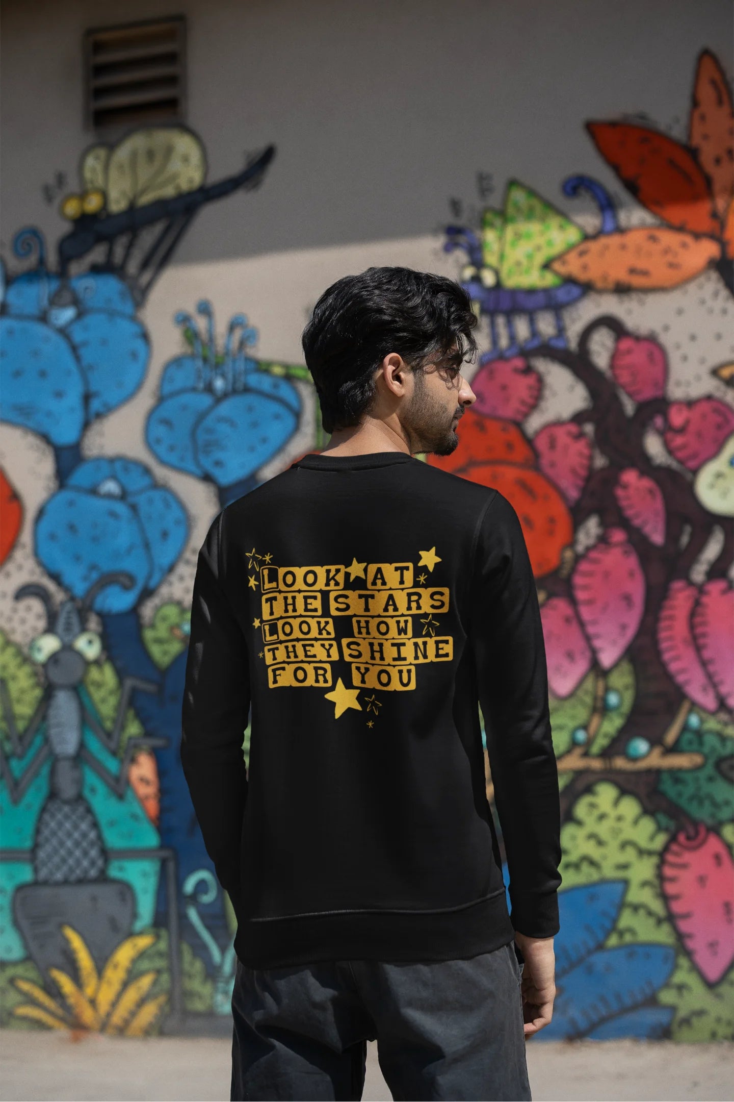 Back view of a male model wearing a black sweatshirt with the "Yellow" album artwork by Coldplay.