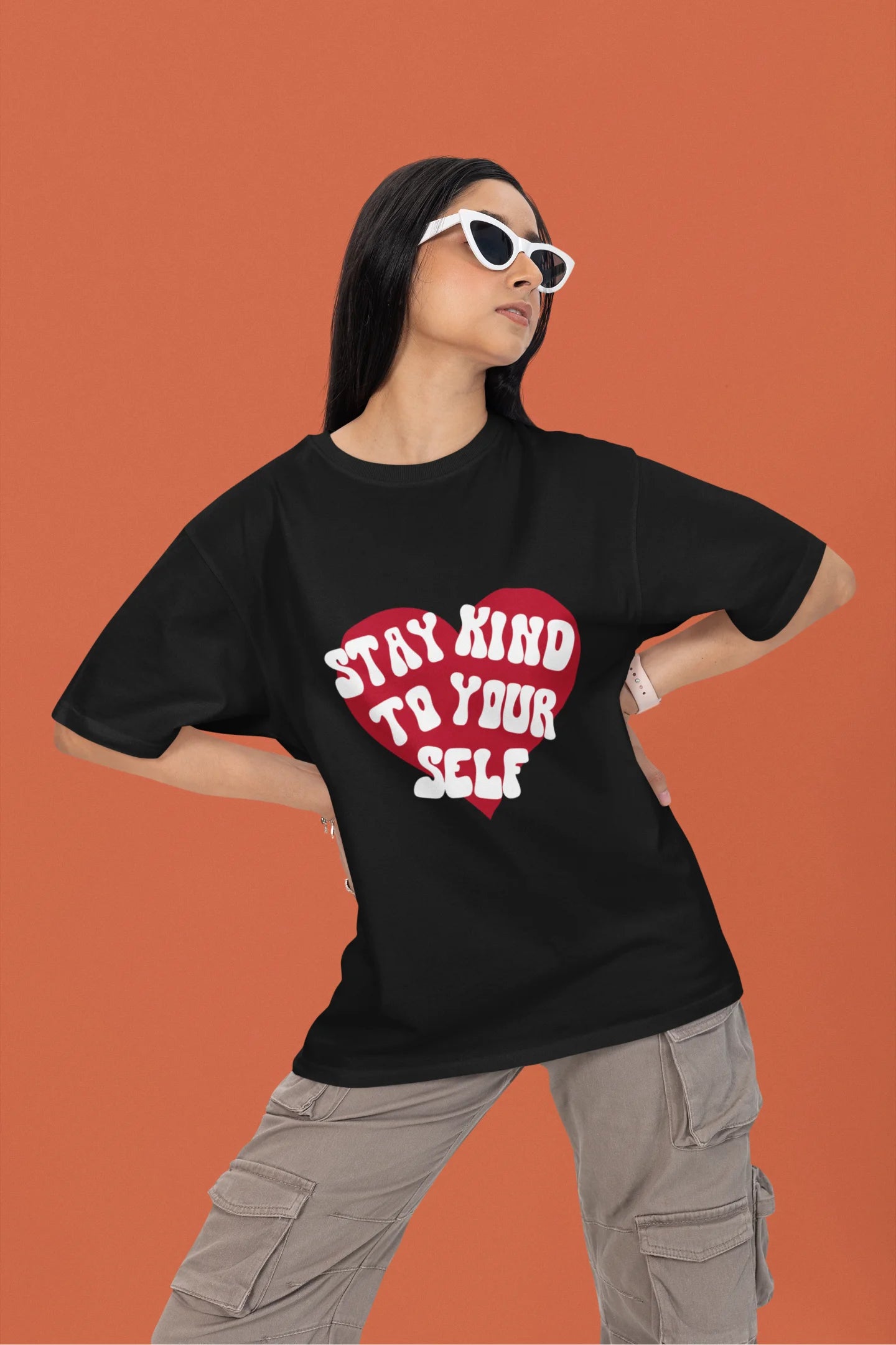 2nd front view of a female model wearing a black oversized t-shirt with the text "Stay Kind" printed on it.