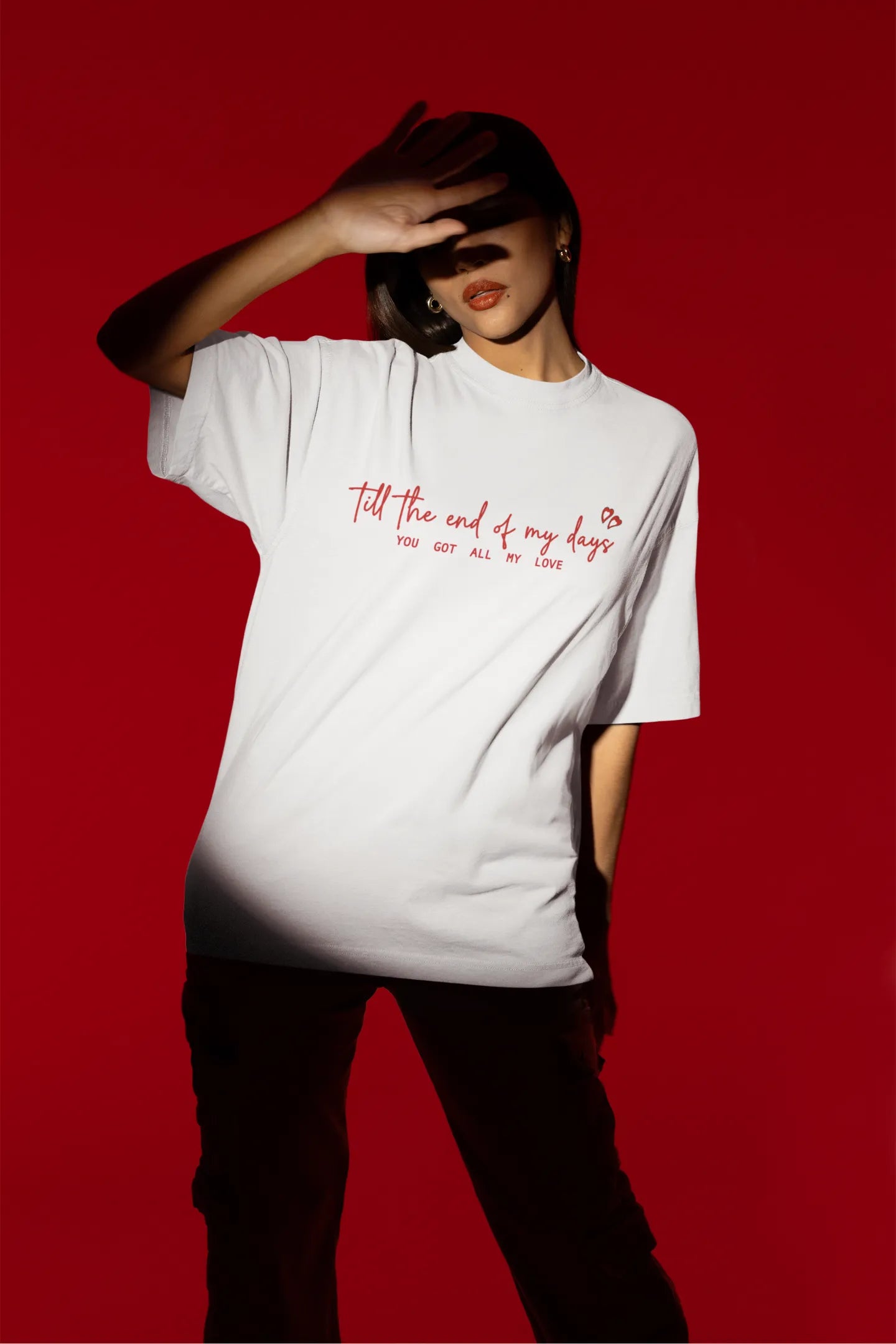 Third front view of a female model wearing a off-white oversized t-shirt with a heart design and the text "All My Love".