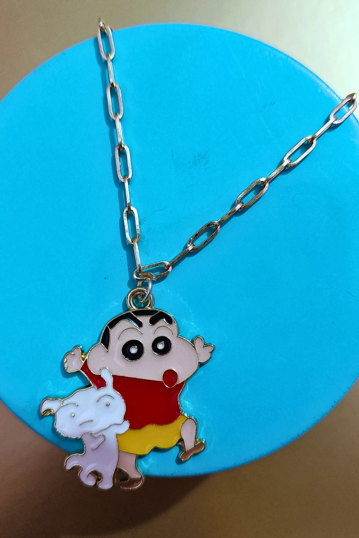 4th front view of a gold chain necklace with a small pendant depicting Shin Chan saying "Hey."