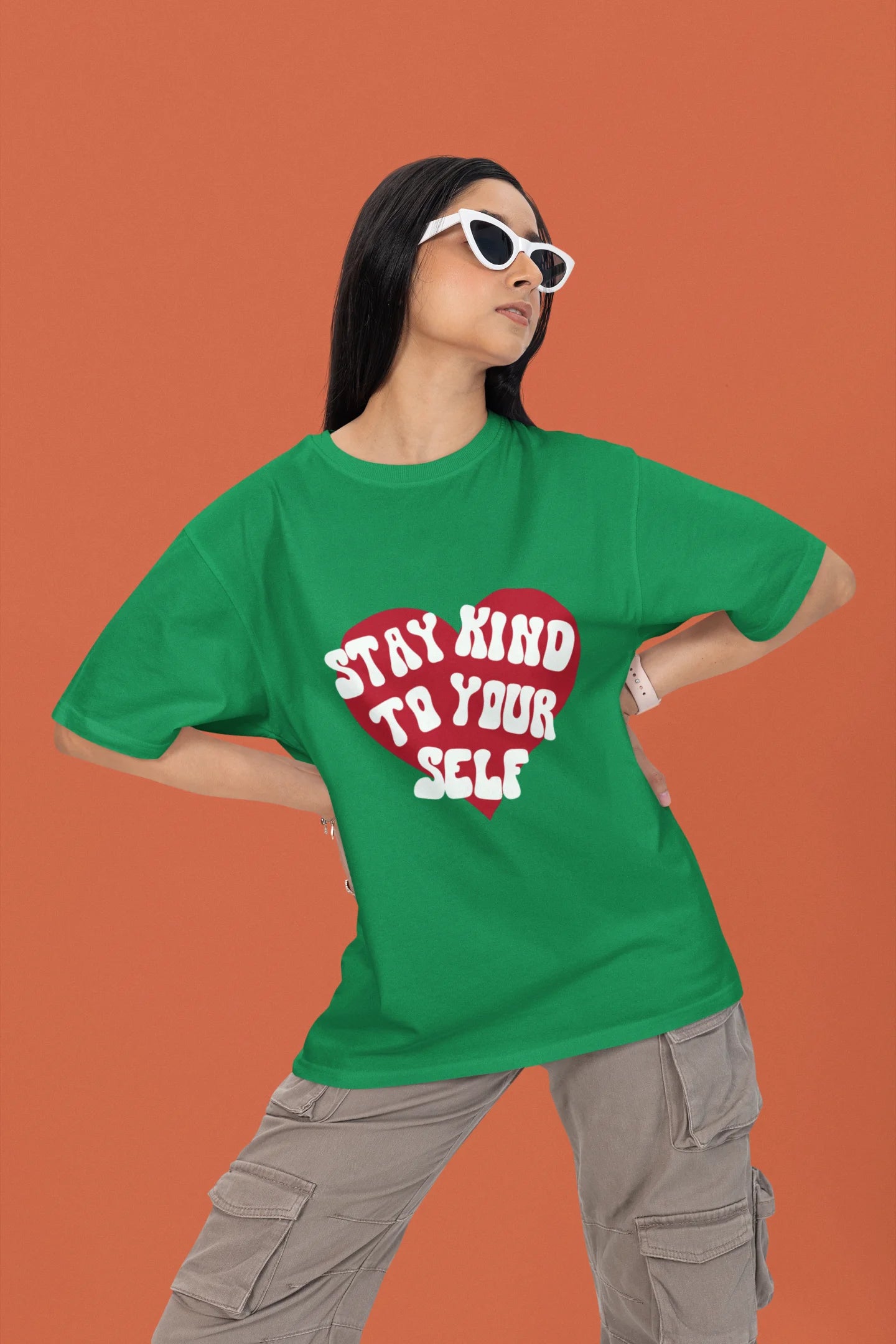 2nd front view of a female model wearing a forest green oversized t-shirt with the text "Stay Kind" printed on it.