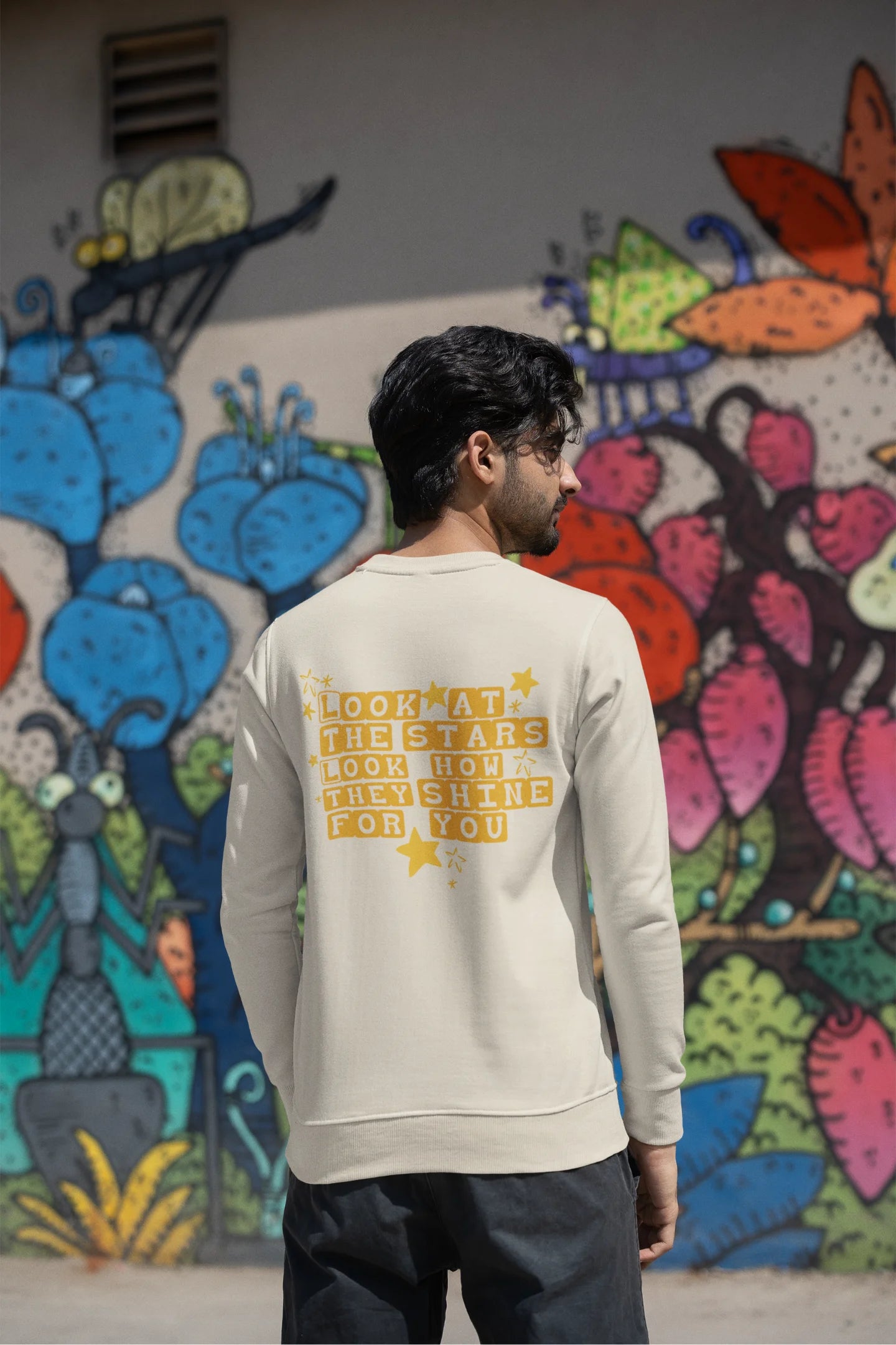 Back view of a male model wearing a cream sweatshirt with the "Yellow" album artwork by Coldplay.