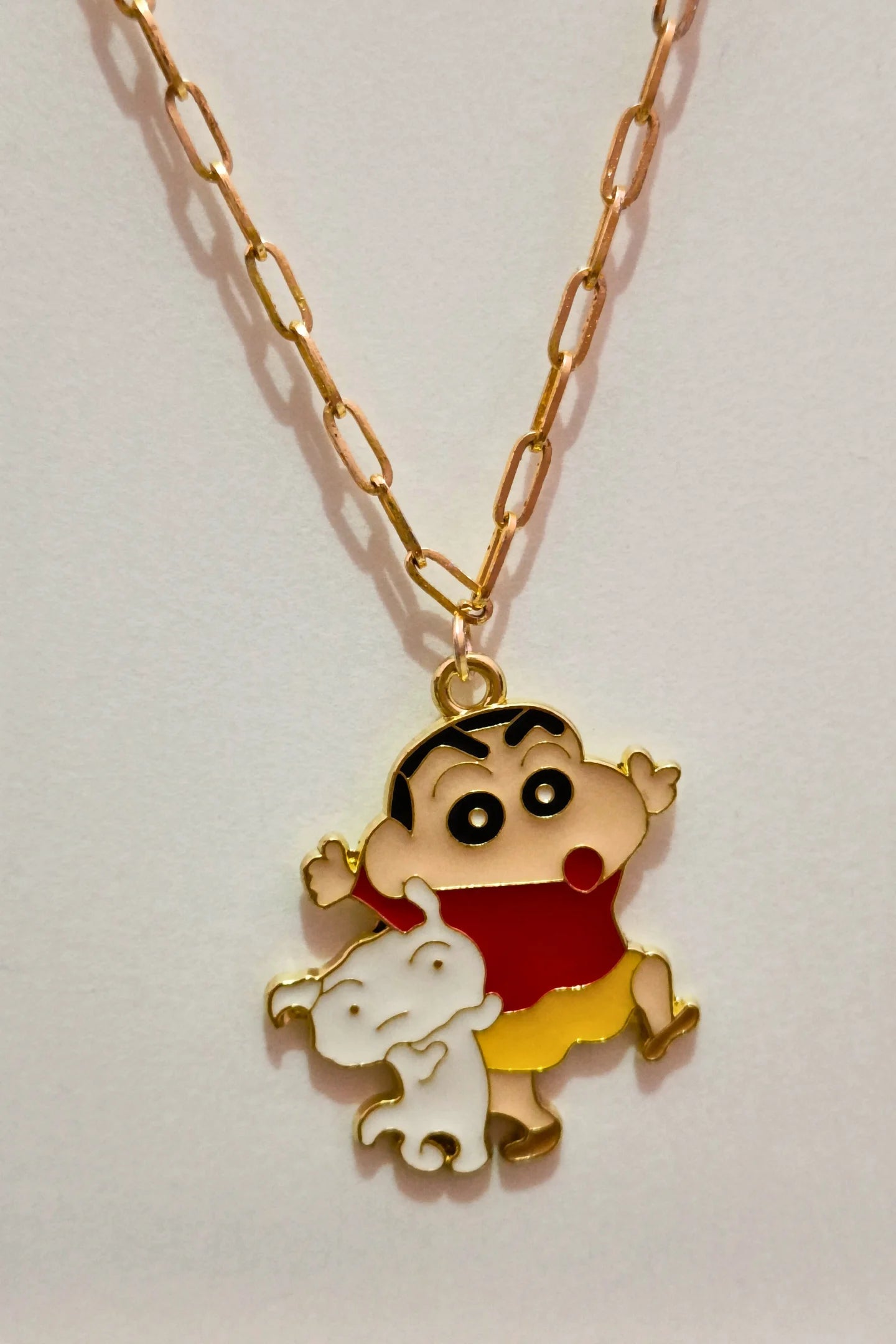 3rd front view of a gold chain necklace with a small pendant depicting Shin Chan saying "Hey."