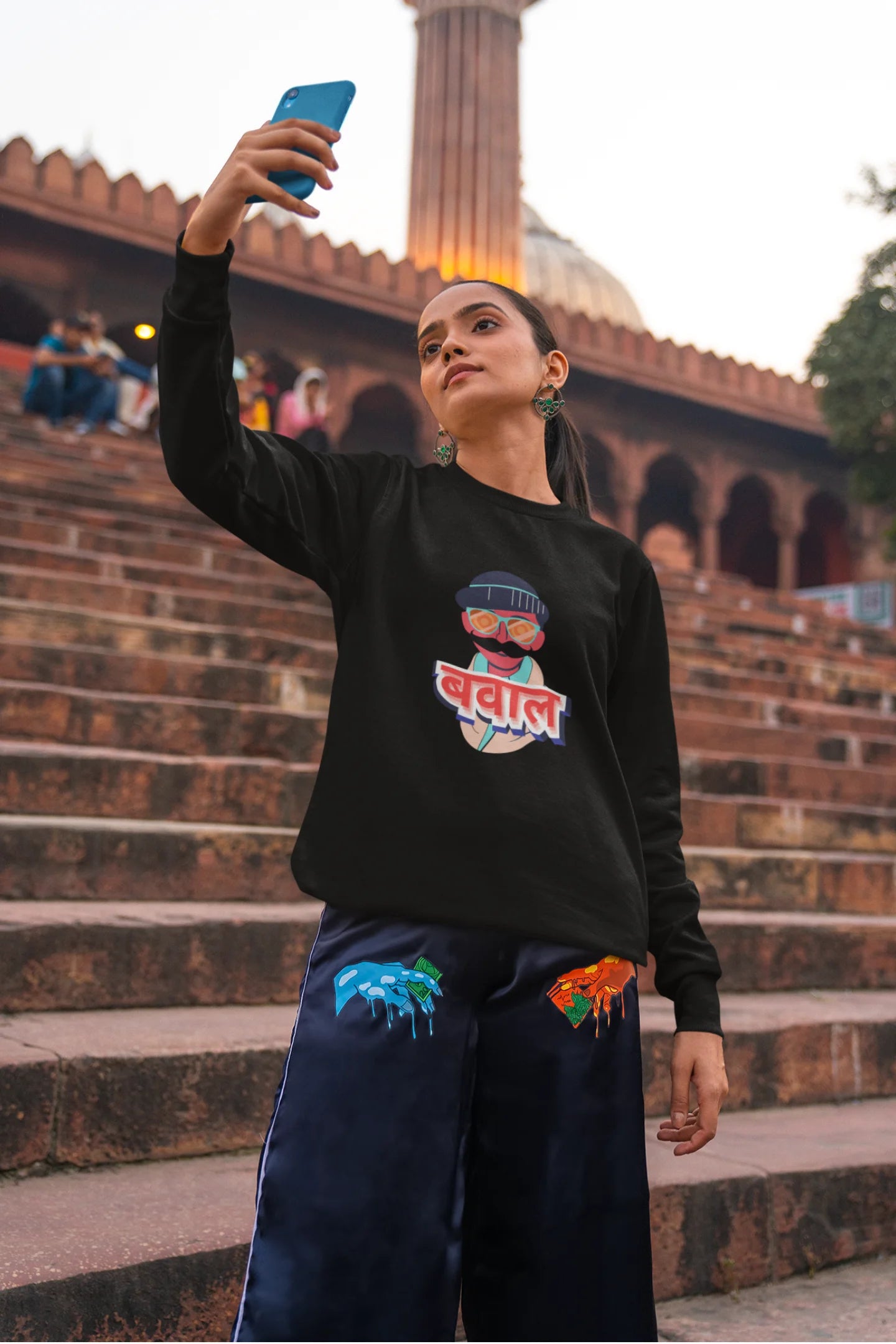 6th front view of a female model wearing a black oversized t-shirt with "Bawaal" in a stylish Hindi.