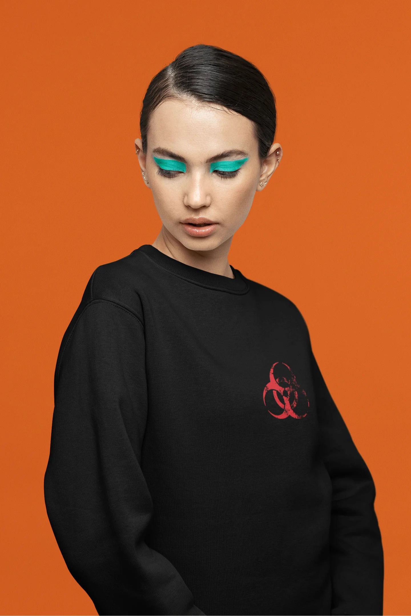 Fourth front view of a female model wearing a black brutalist sweatshirt with a stylized, concrete-like image of an abstract statue and the word "Experiment" prominently displayed.