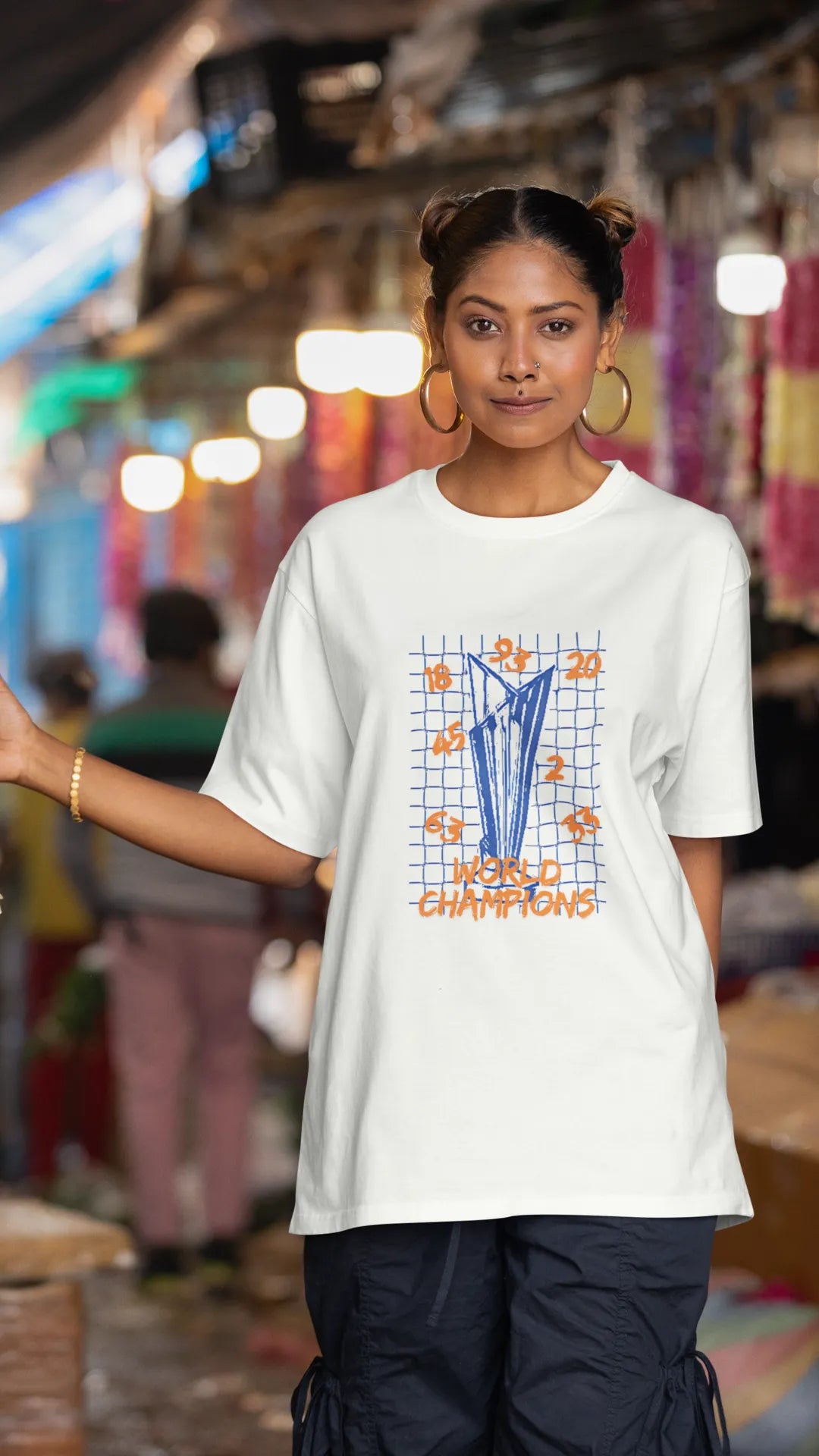 Second front image of female model wearing an off-white oversized t-shirt featuring the World Cup 2024 trophy with the text "World Champions" underneath. Ideal for Indian cricket fans celebrating their team's victory.