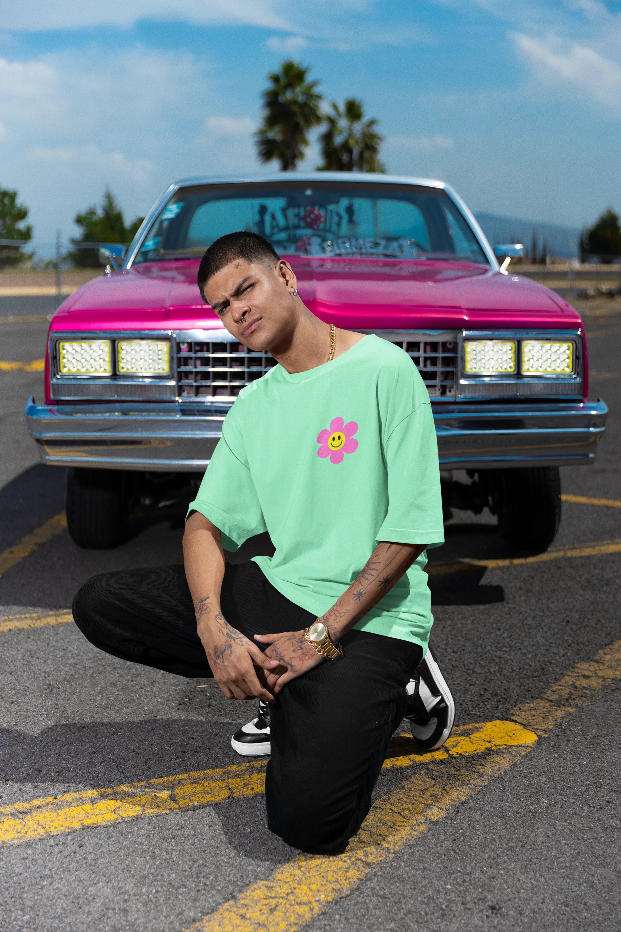 Right side view of a male model wearing an oversized mint green t-shirt with a positive message "Keep Smiling" surrounded by colorful flowers and a smiley face emoji. Ideal for those who love cheerful clothing and spreading positivity.