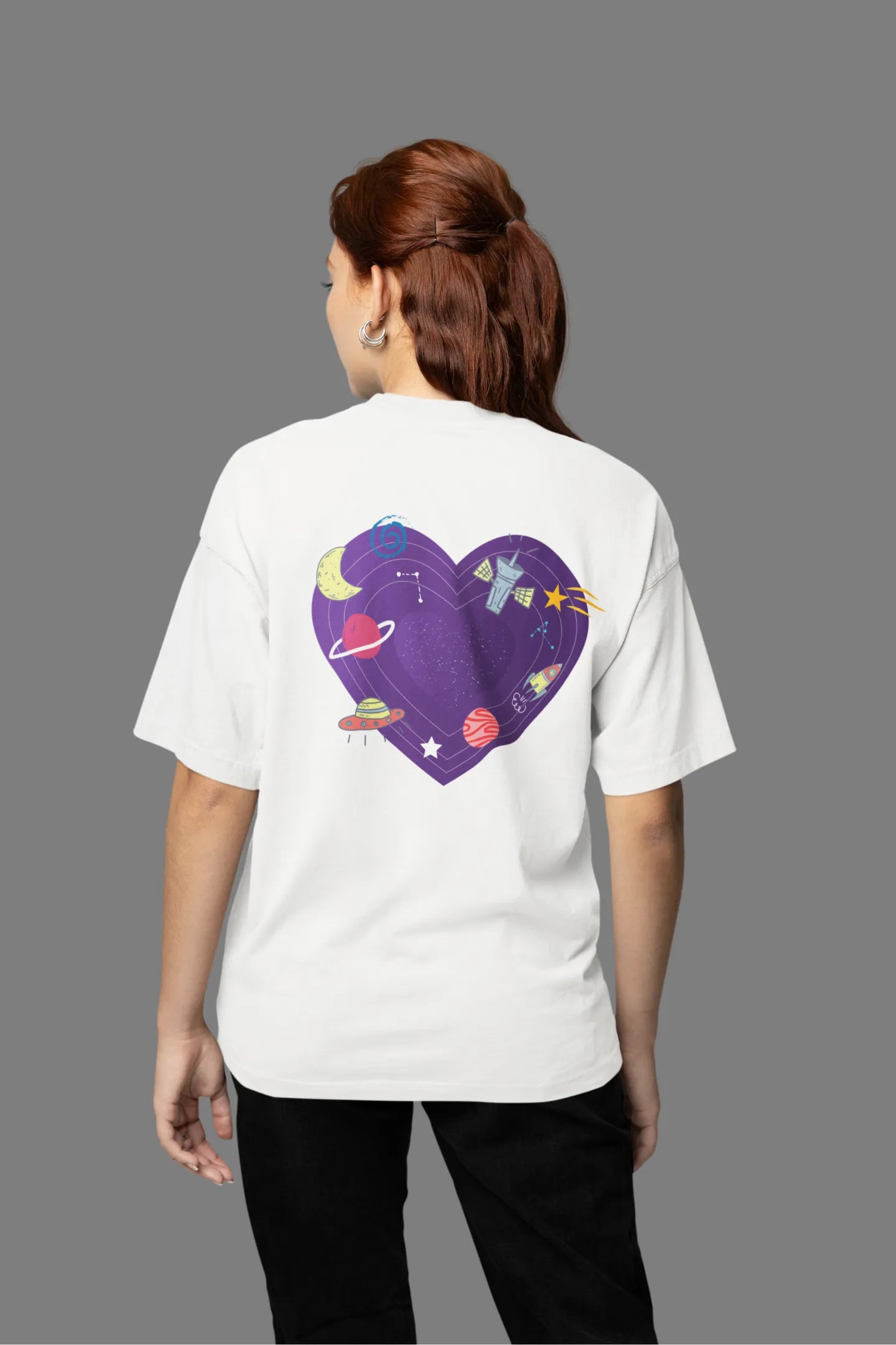 Back view of a female model wearing an white oversized t-shirt with the "Paradise" album artwork by Coldplay.
