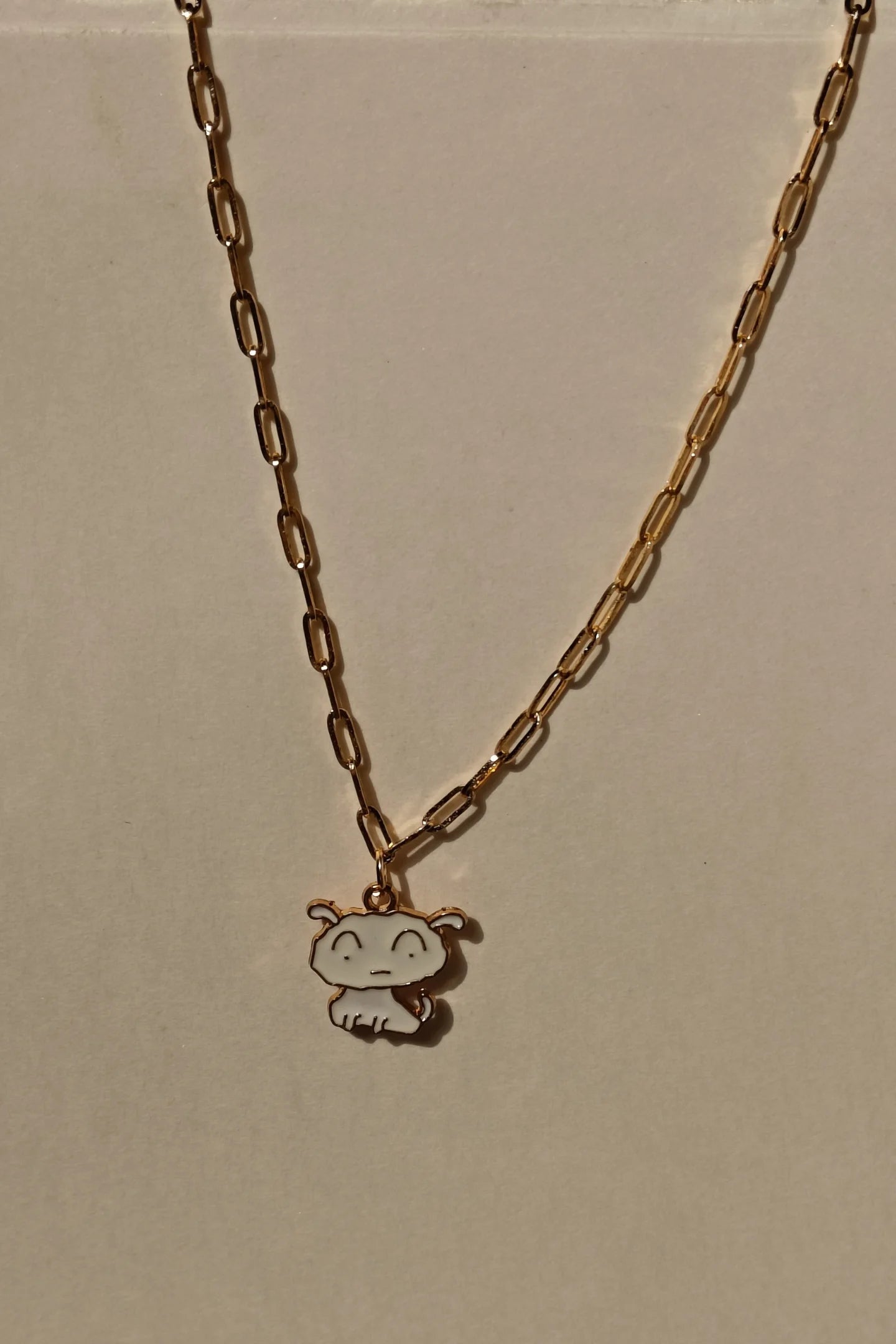 3rd view of a gold chain necklace with a small pendant depicting Shero from the anime Shin Chan.