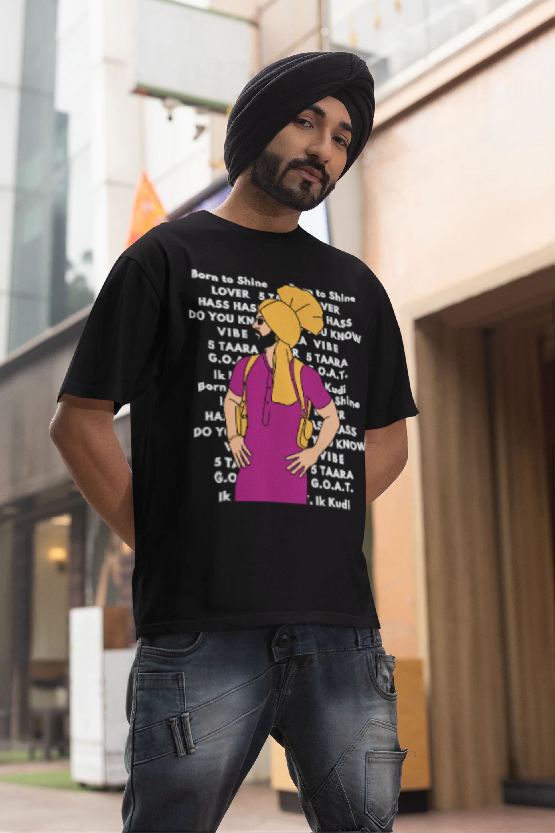 Second image of a male model wearing a black oversized t-shirt with a Diljit Dosanjh portrait on a t-shirt with his album titles written in the background.