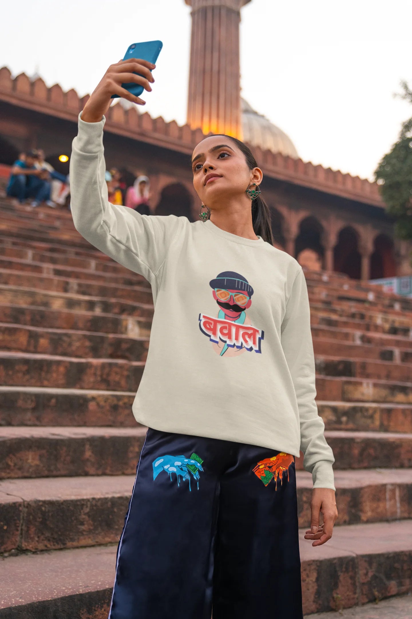 5th front view of a female model wearing a cream oversized t-shirt with "Bawaal" in a stylish Hindi.