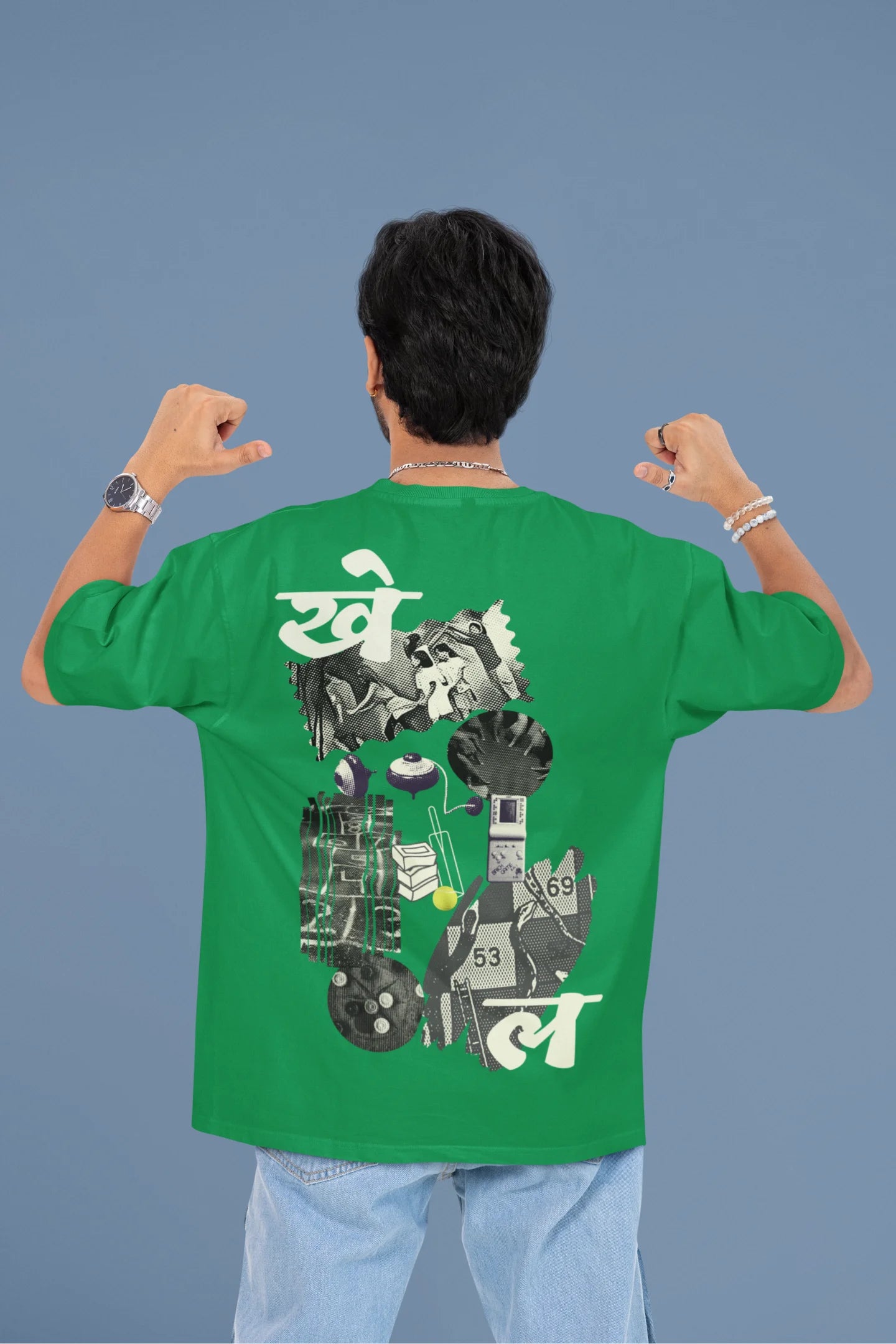 Back view of a male model wearing a forest green oversized t-shirt featuring a collage of illustrations or symbols representing various childhood games commonly played by kids in India.