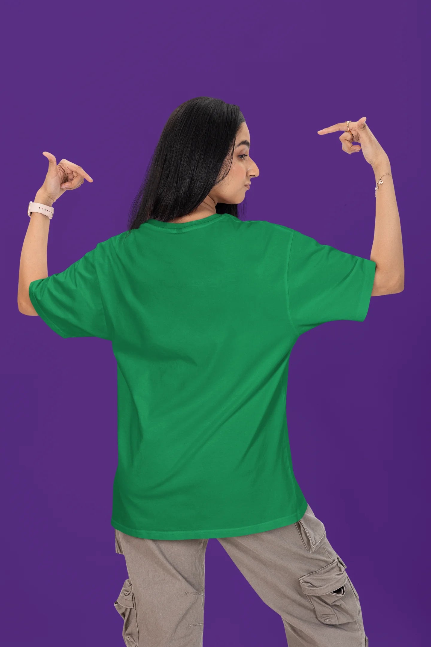 Back view of a female model wearing a forest green oversized t-shirt with the text "Stay Kind" printed on it.