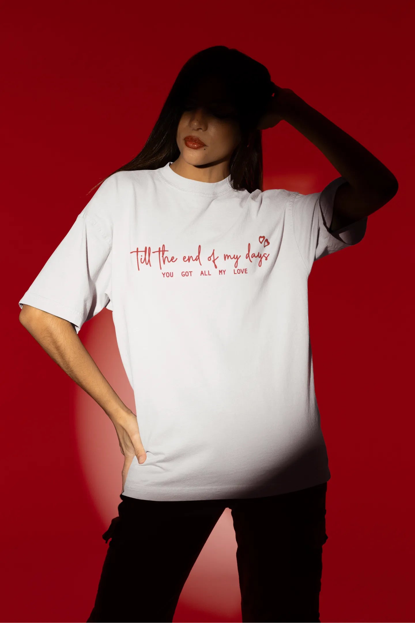 Fourth front view of a female model wearing a off-white oversized t-shirt with a heart design and the text "All My Love".
