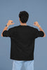 Back view of a male model wearing a black oversized t-shirt with the text 