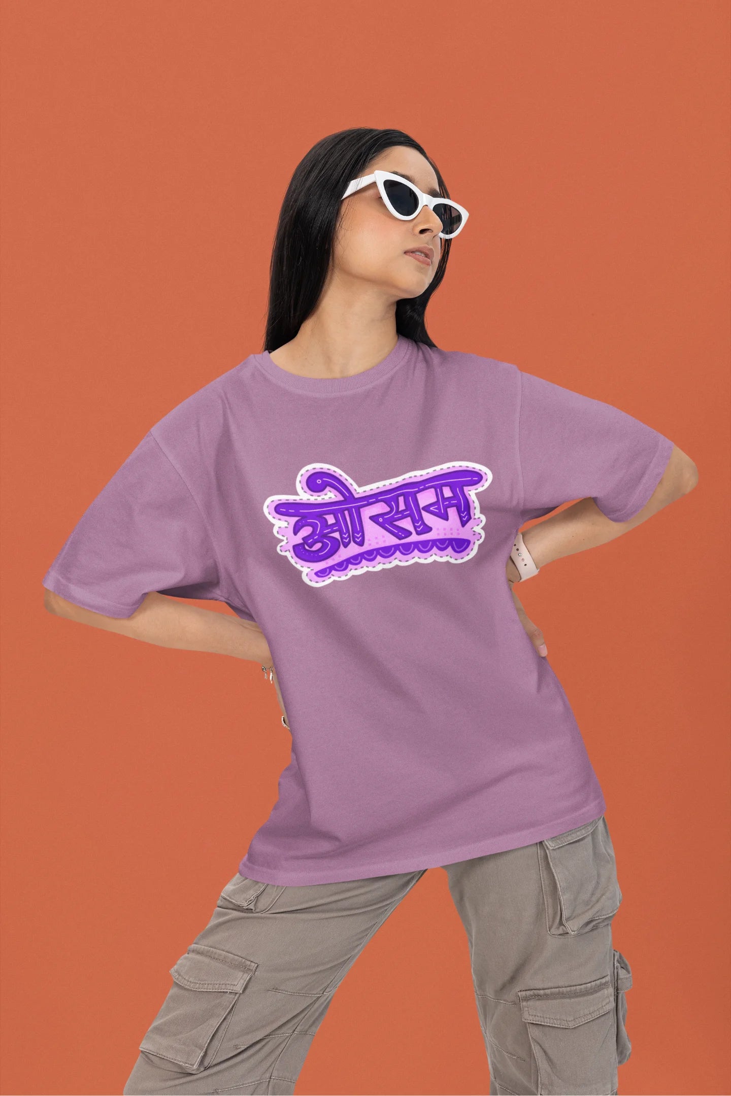 2nd front view of a female model wearing a dirty purple colored oversized graphic t-shirt featuring the word "awesome" in a Hindi script.