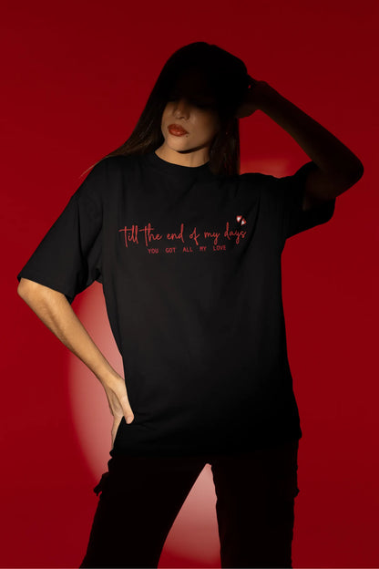 Fourth front view of a female model wearing a black oversized t-shirt with a heart design and the text "All My Love".