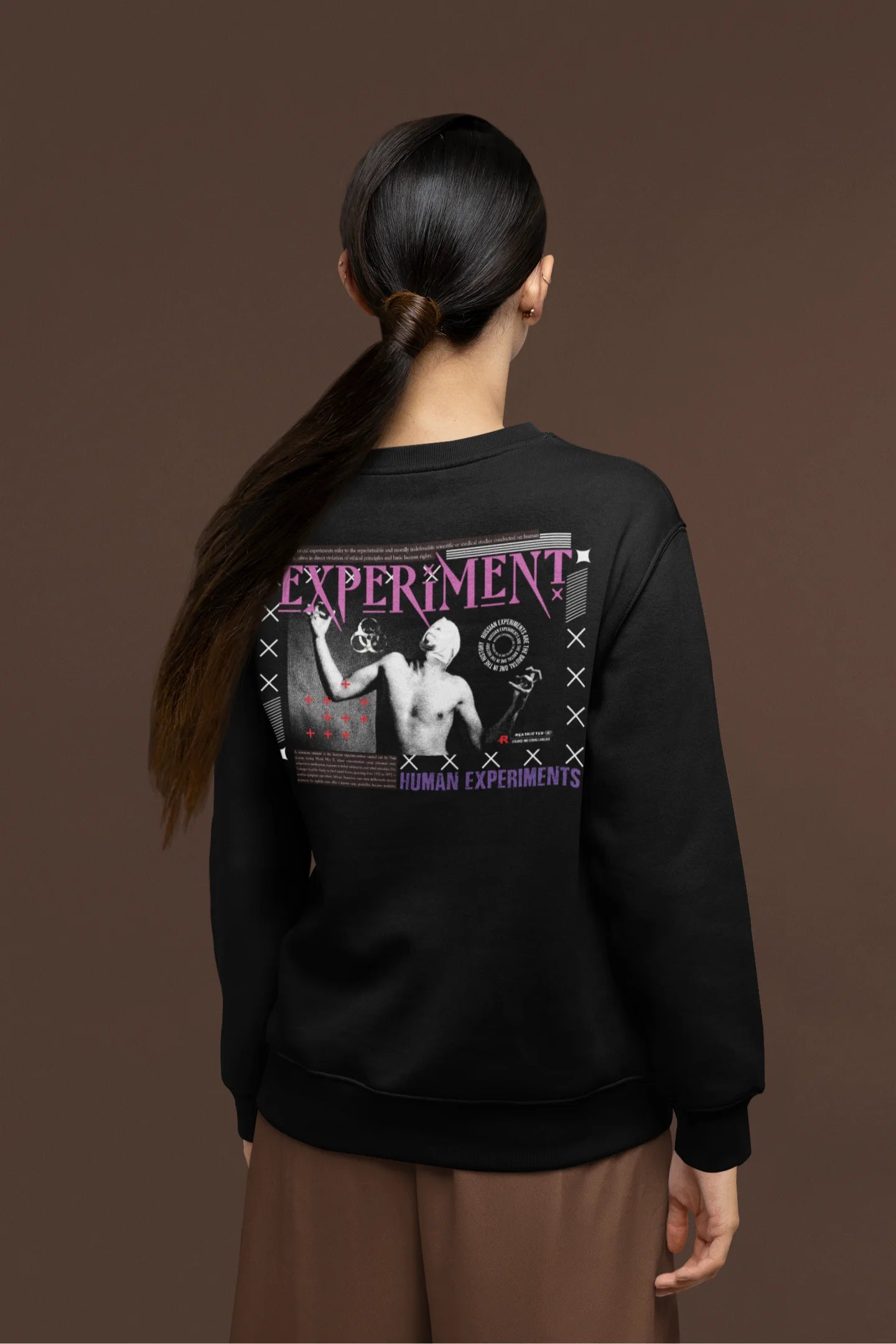 Back view of a female model wearing a black brutalist sweatshirt with a stylized, concrete-like image of an abstract statue and the word "Experiment" prominently displayed.