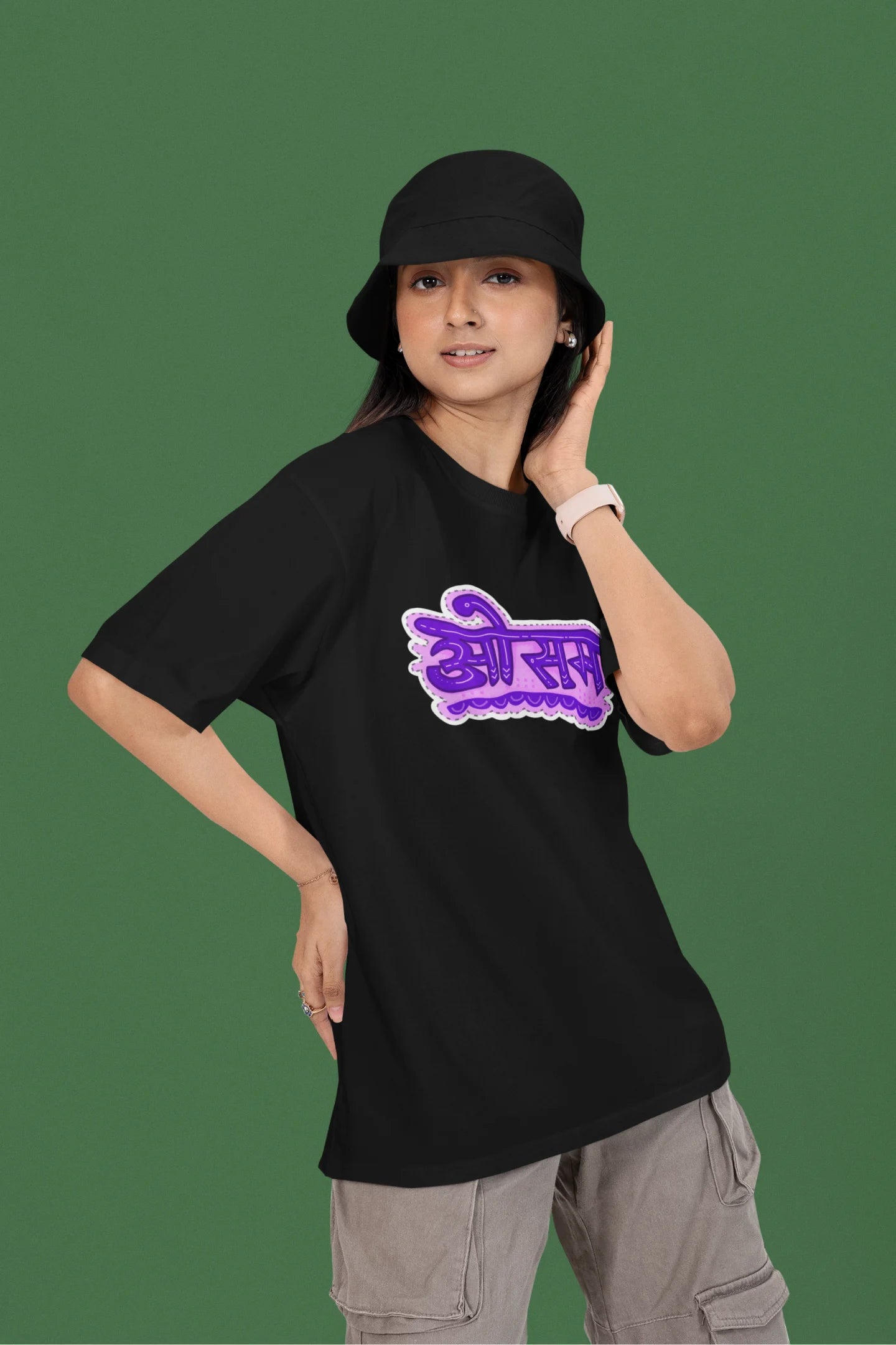 3rd front view of a female model wearing a black colored oversized graphic t-shirt featuring the word "awesome" in a Hindi script.
