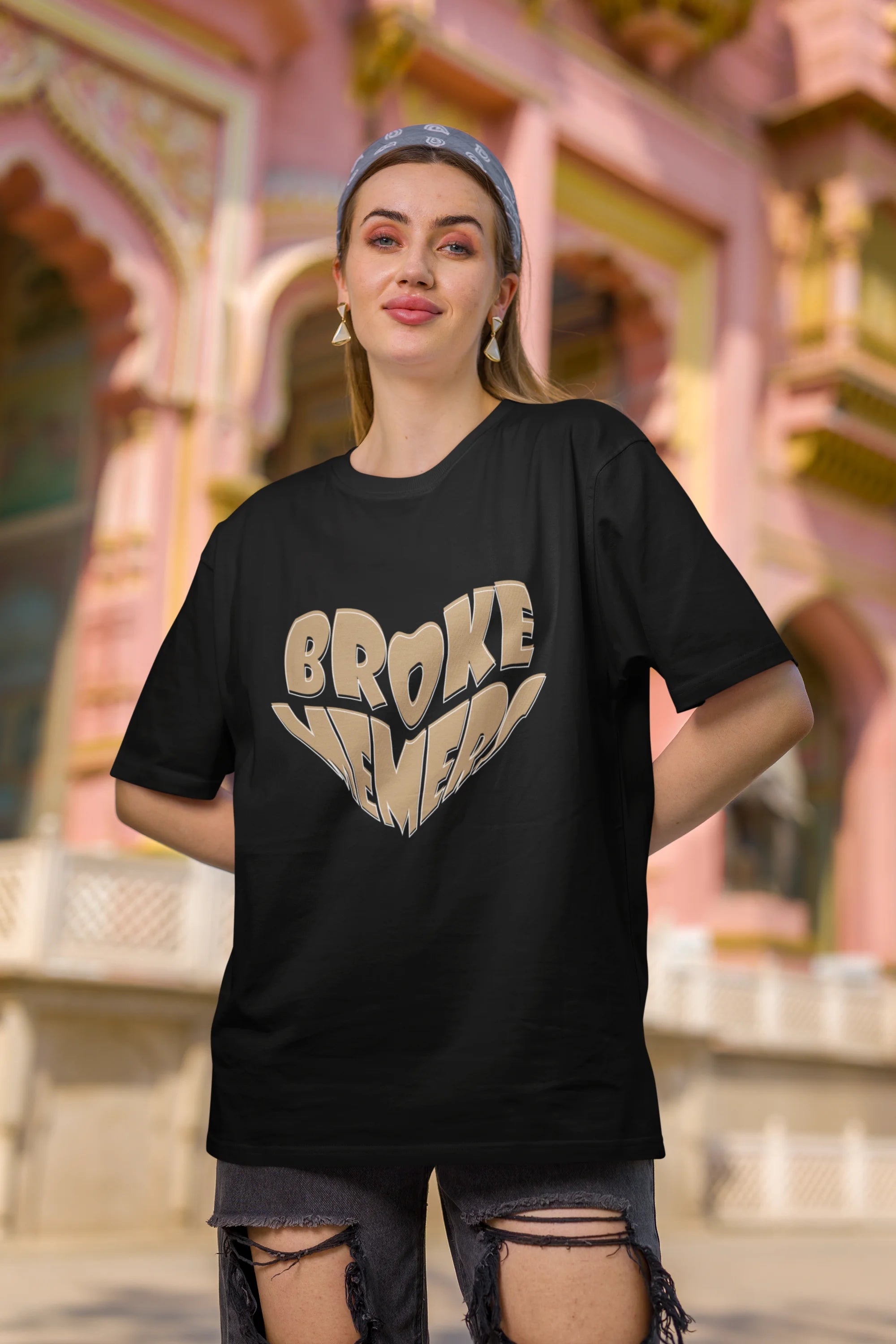 Second front view of female model wearing a black oversized t-shirt featuring the "Broke Memers" logo creatively shaped like a heart. Ideal for fans of Broke Memers who love quality and fashionable clothing.