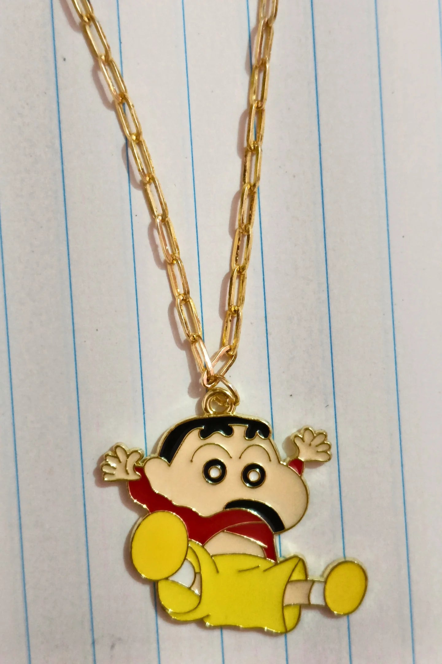 First view of a gold chain necklace with a small pendant depicting Shin Chan jumping in the air and shouting "Hurray!