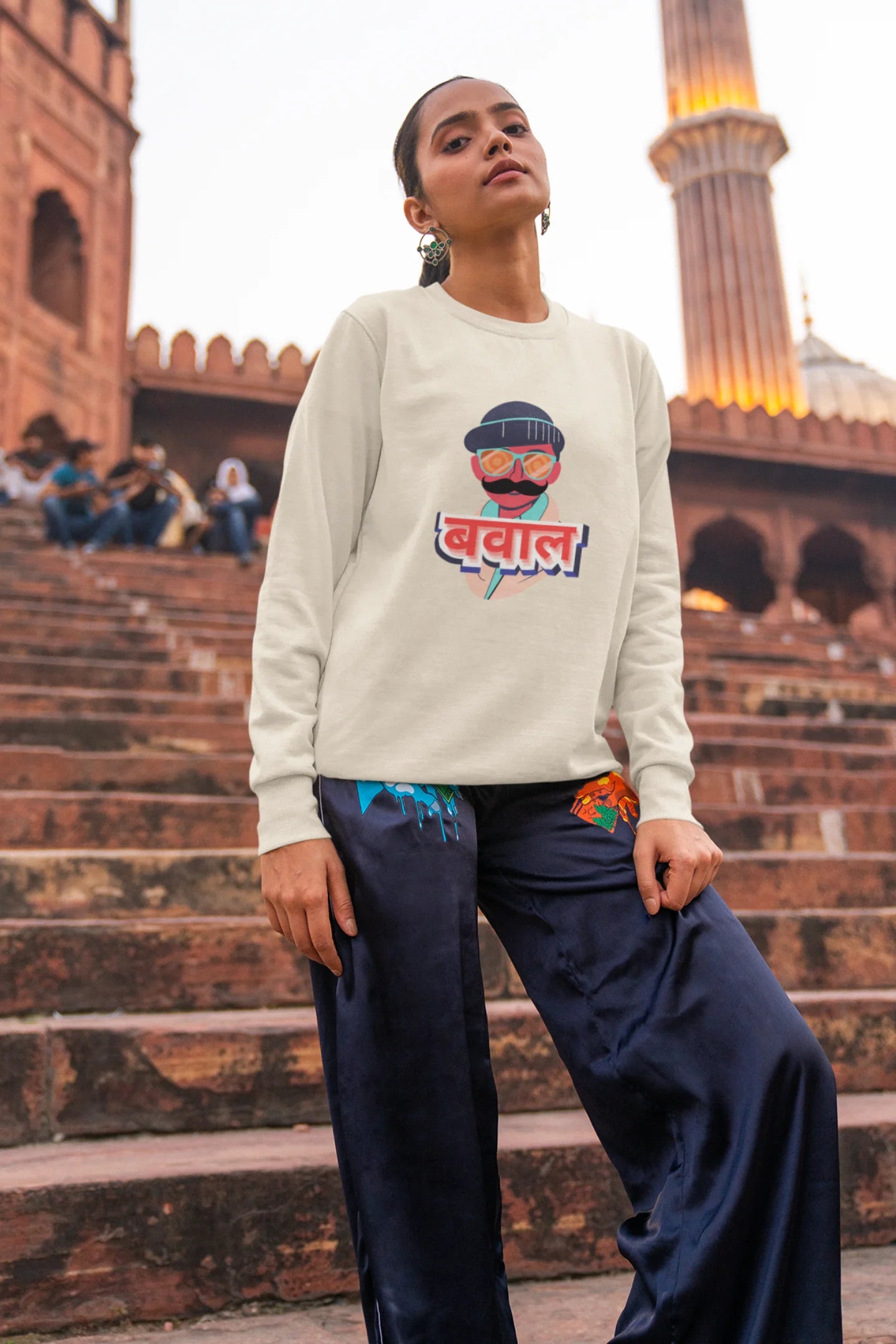 4th front view of a female model wearing a cream oversized t-shirt with "Bawaal" in a stylish Hindi.